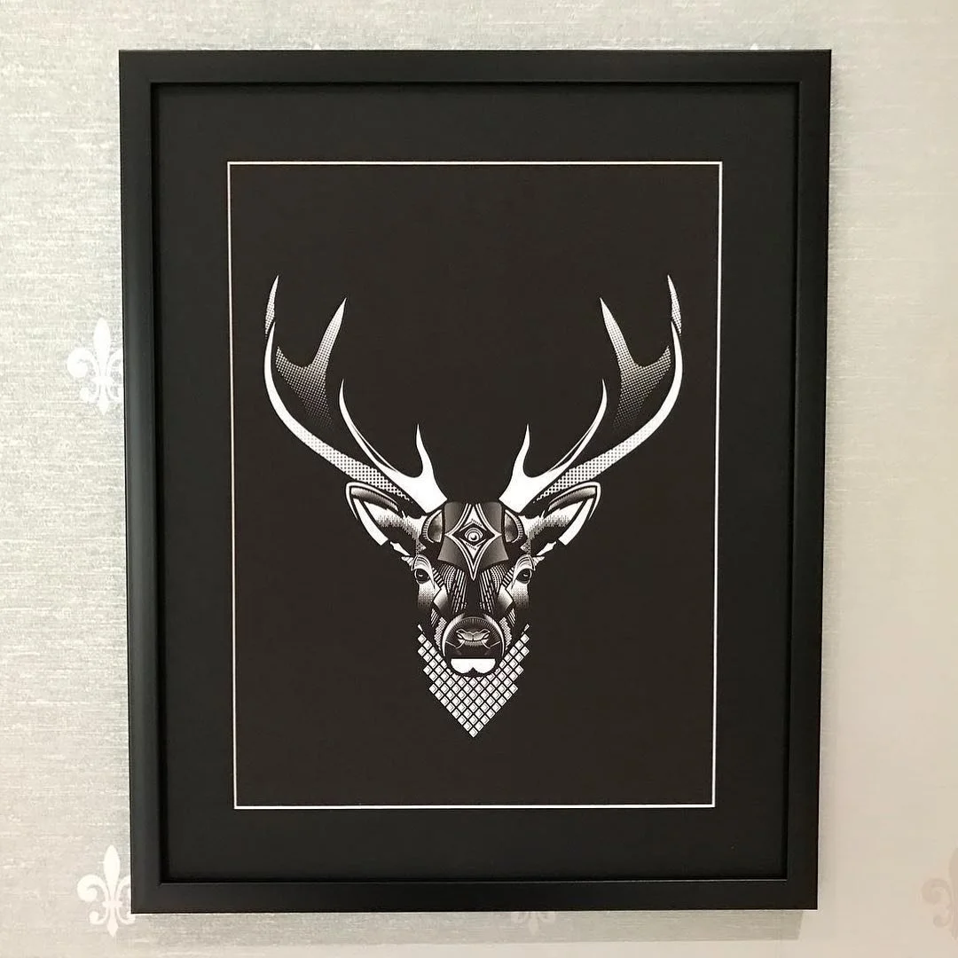 Black and white framed artwork of a deer's head with large antlers, depicted in a geometric and abstract style.