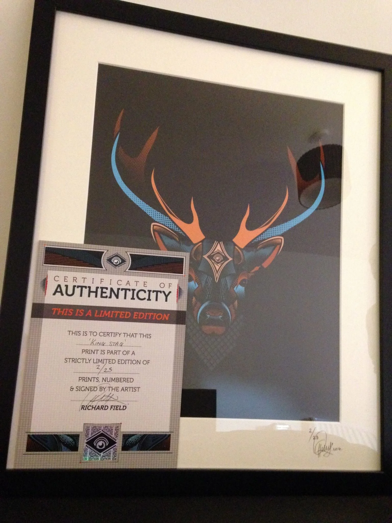 Framed artwork of a stylized deer head with large antlers, featuring geometric and abstract design elements, along with a certificate of authenticity for limited edition print 2 out of 25 signed by artist Richard Field.
