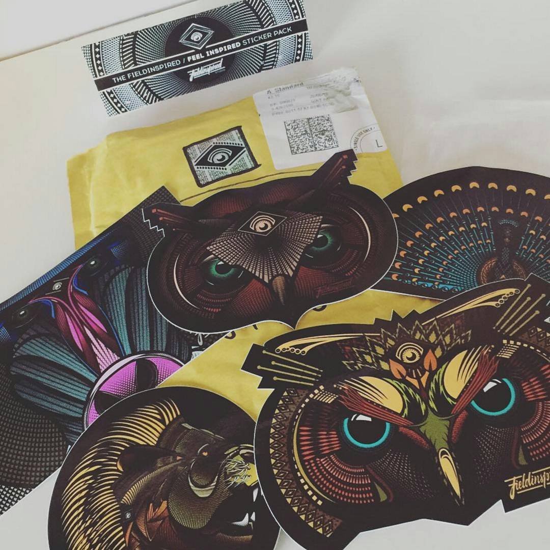 Set of colorful, geometric owl stickers with intricate patterns, along with packaging and postal materials in the background.
