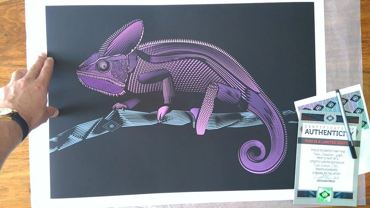 Colorful technical illustration of a chameleon on a dark background, with a certificate of authenticity and a pen beside it.