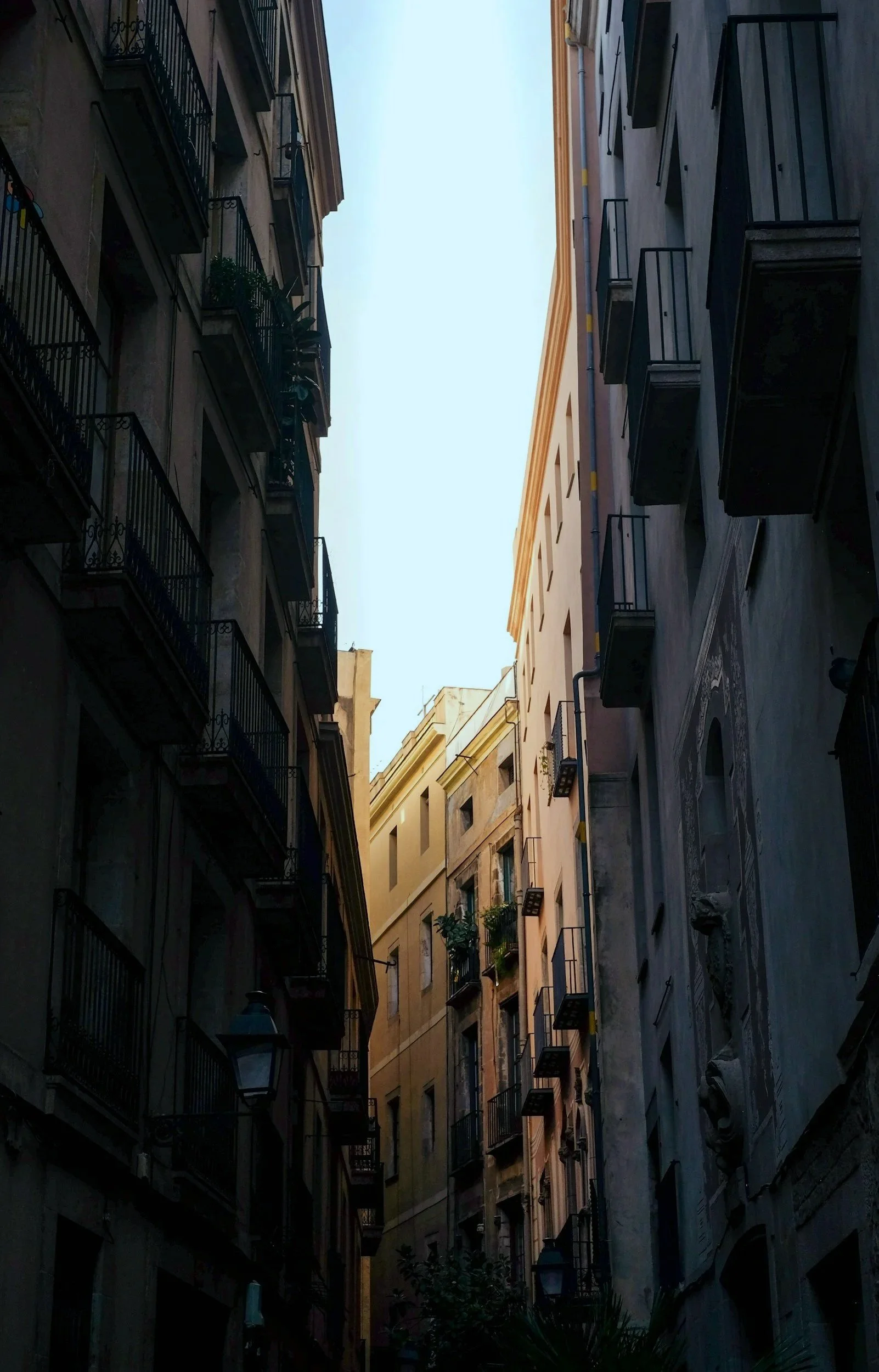 Tall building alleyway with multiple pastel-colored buildings, narrow street, and clear sky above.