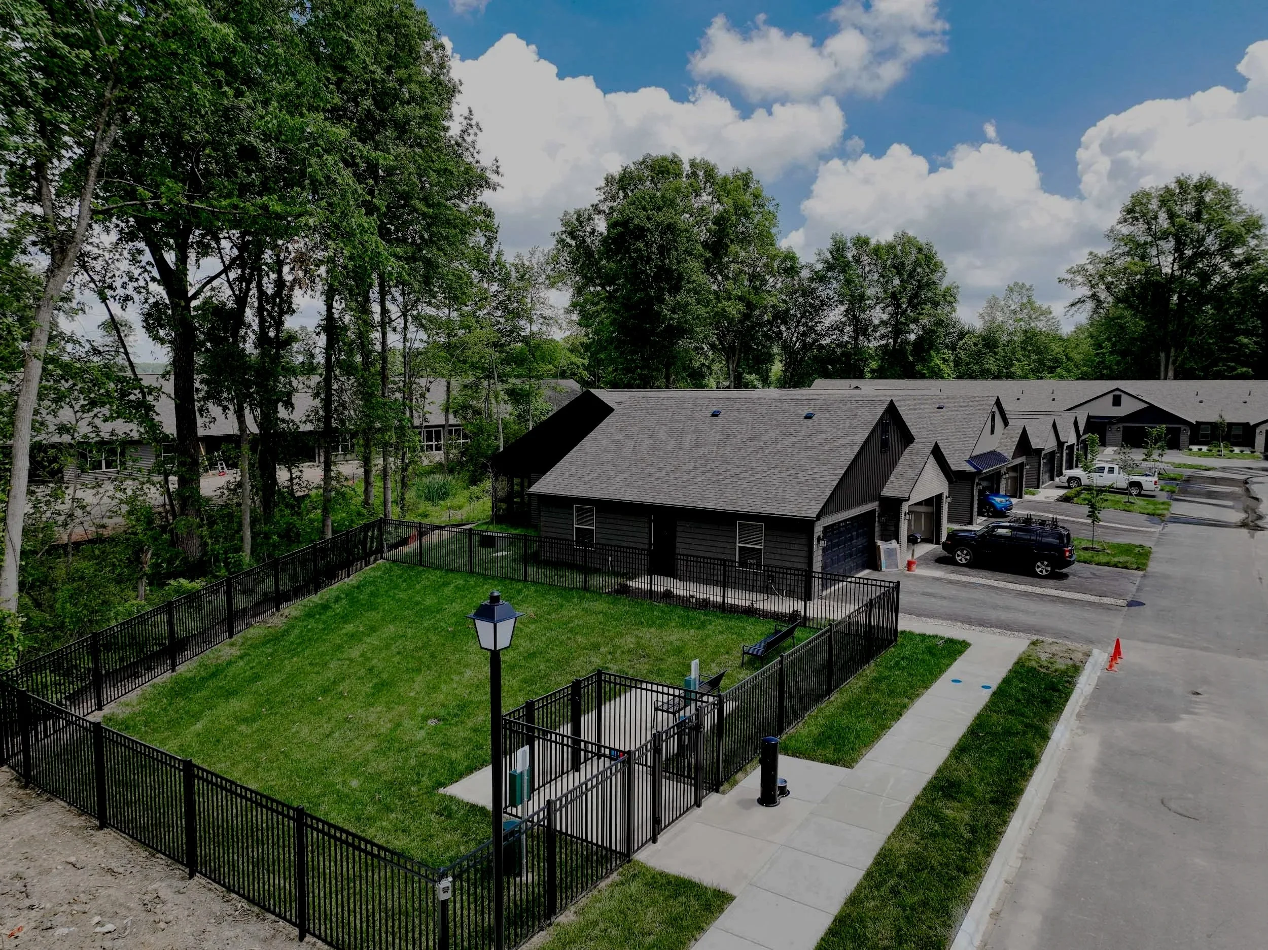 Aerial image of the community's private dog park. Grassy area spanning approximately 30 feet long and 40 feet wide with well-kept green grass and a black metal fence.