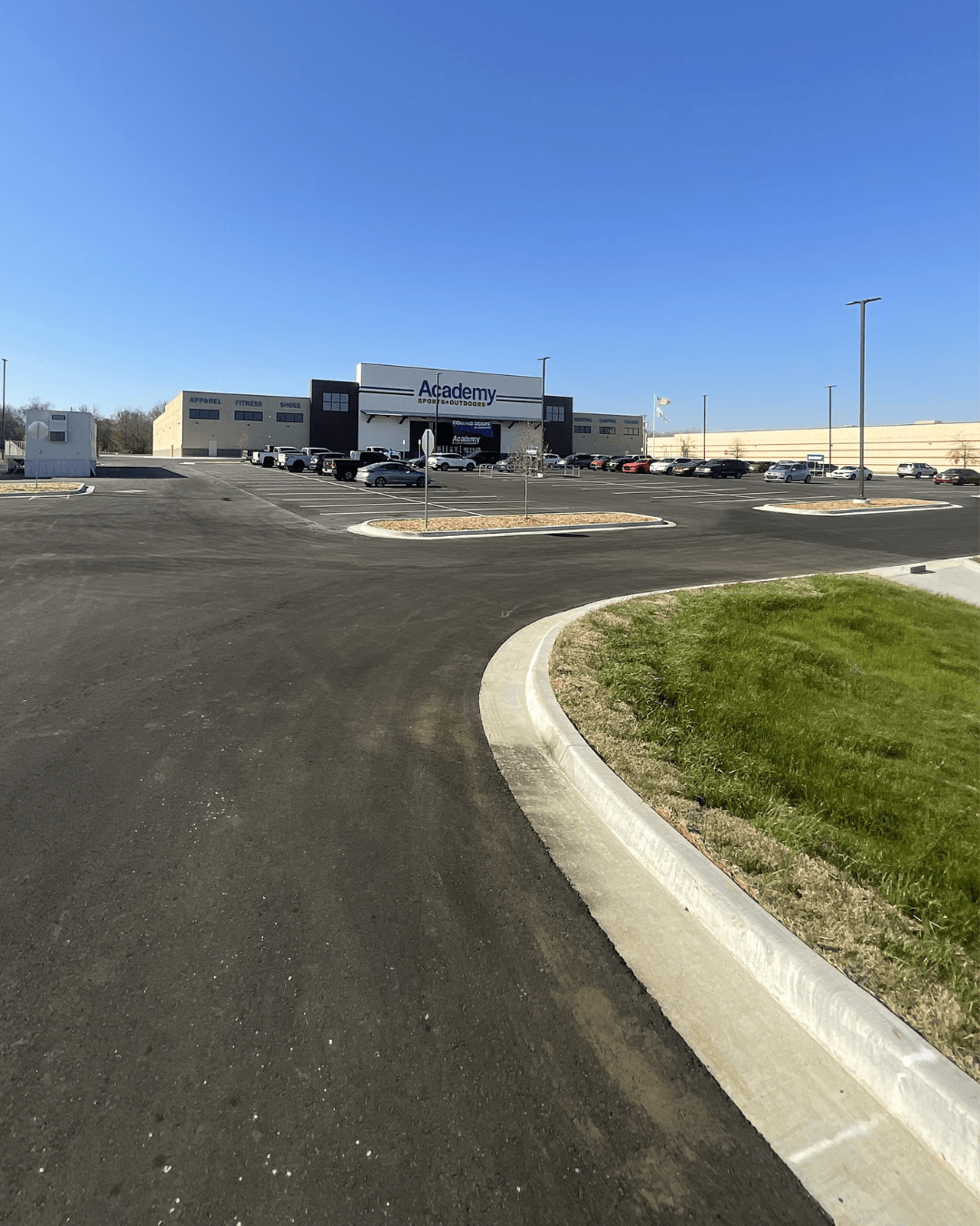 New asphalt parking lot with concrete curb and gutter in front of large retail store, completed site paving and concrete work