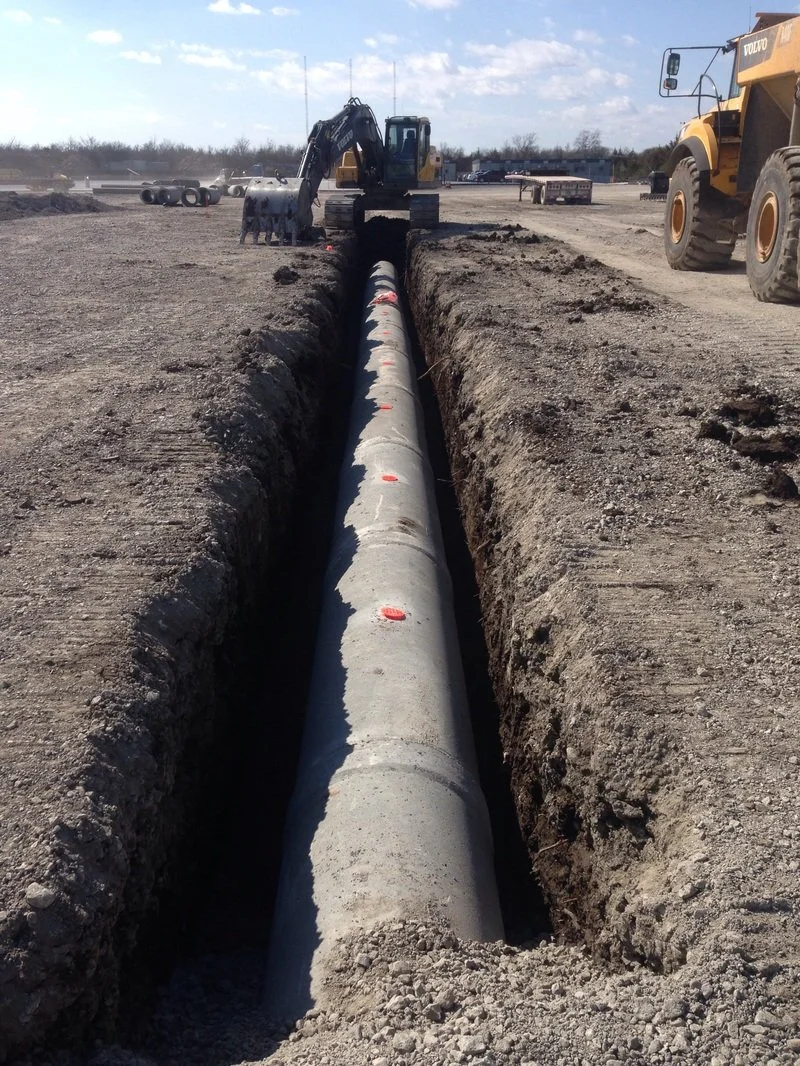Storm sewer pipe installed in an excavated trench during underground drainage work.