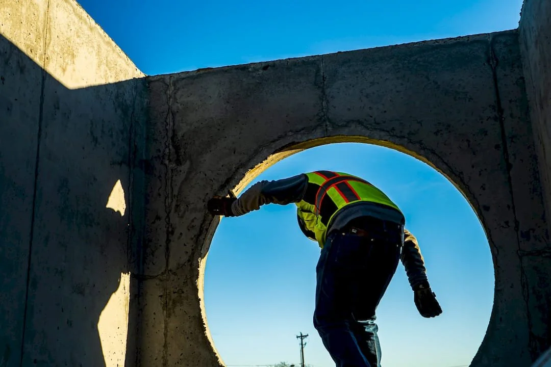 Man coming out of a concrete structure surrounded by a blue sky.