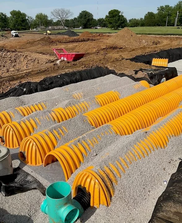 Storm drainage system with aggregate bedding and underground piping shown.