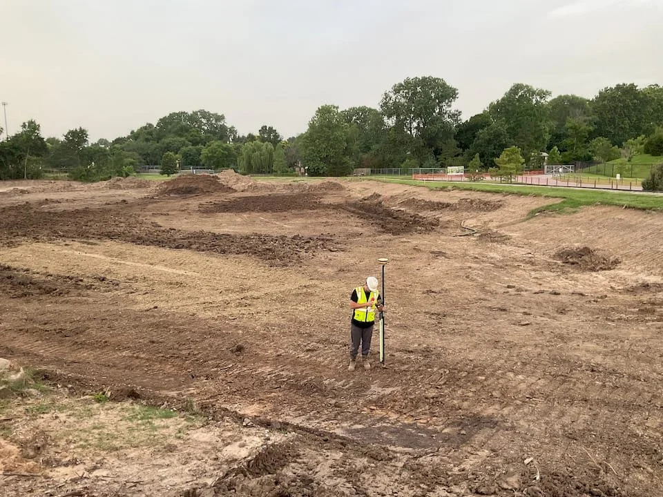 Man on a job site in a clear field with a base and rover.