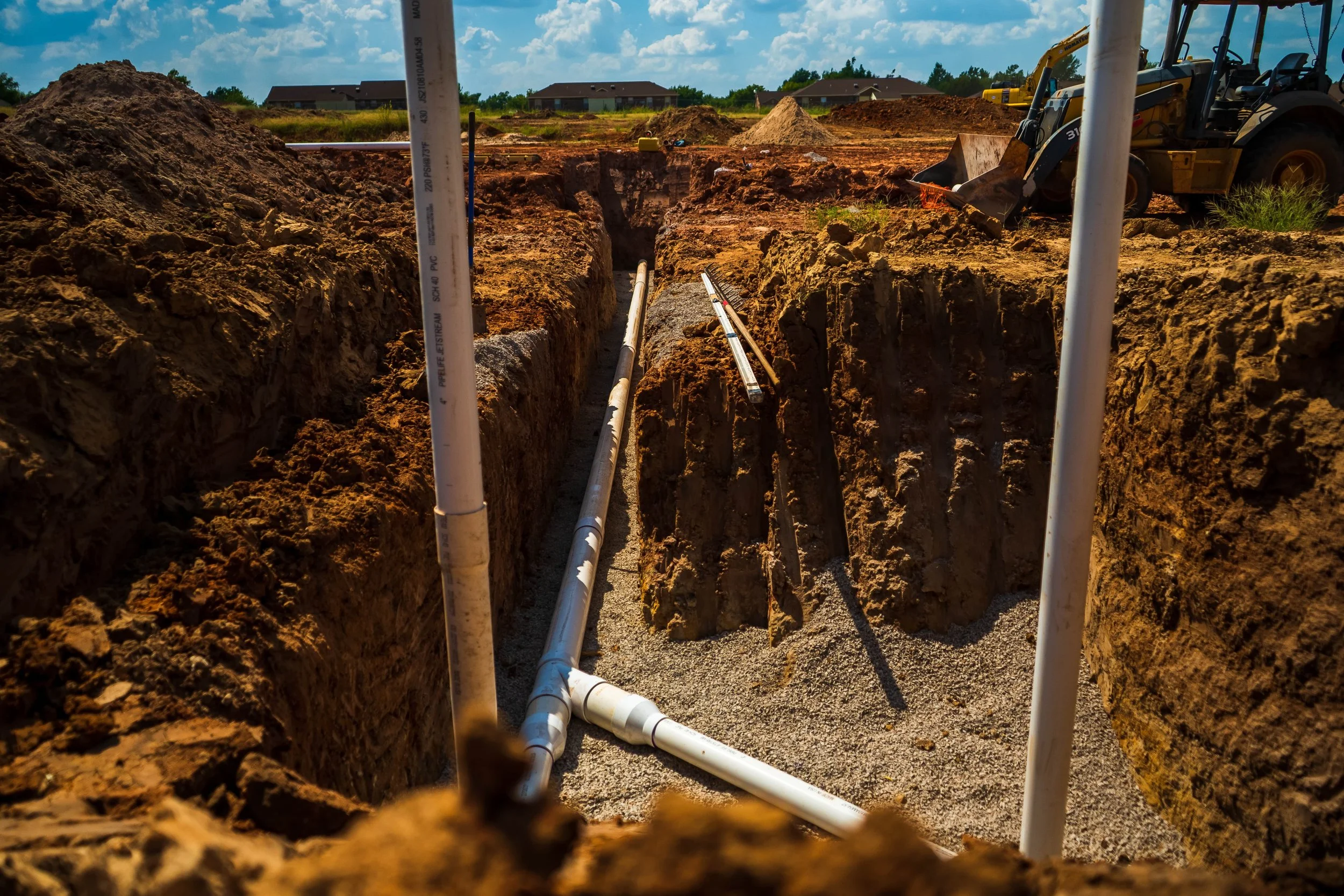 PVC utility piping installed in open trench on a construction site