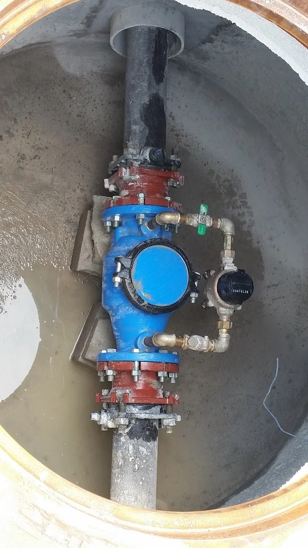 Backflow detector check assembly installed on a water line inside a concrete vault.