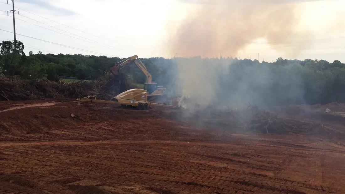 Heavy equipment clearing trees and vegetation during site preparation.