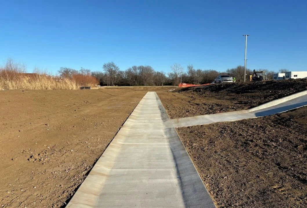 New concrete sidewalk and final grading shown on a construction site.