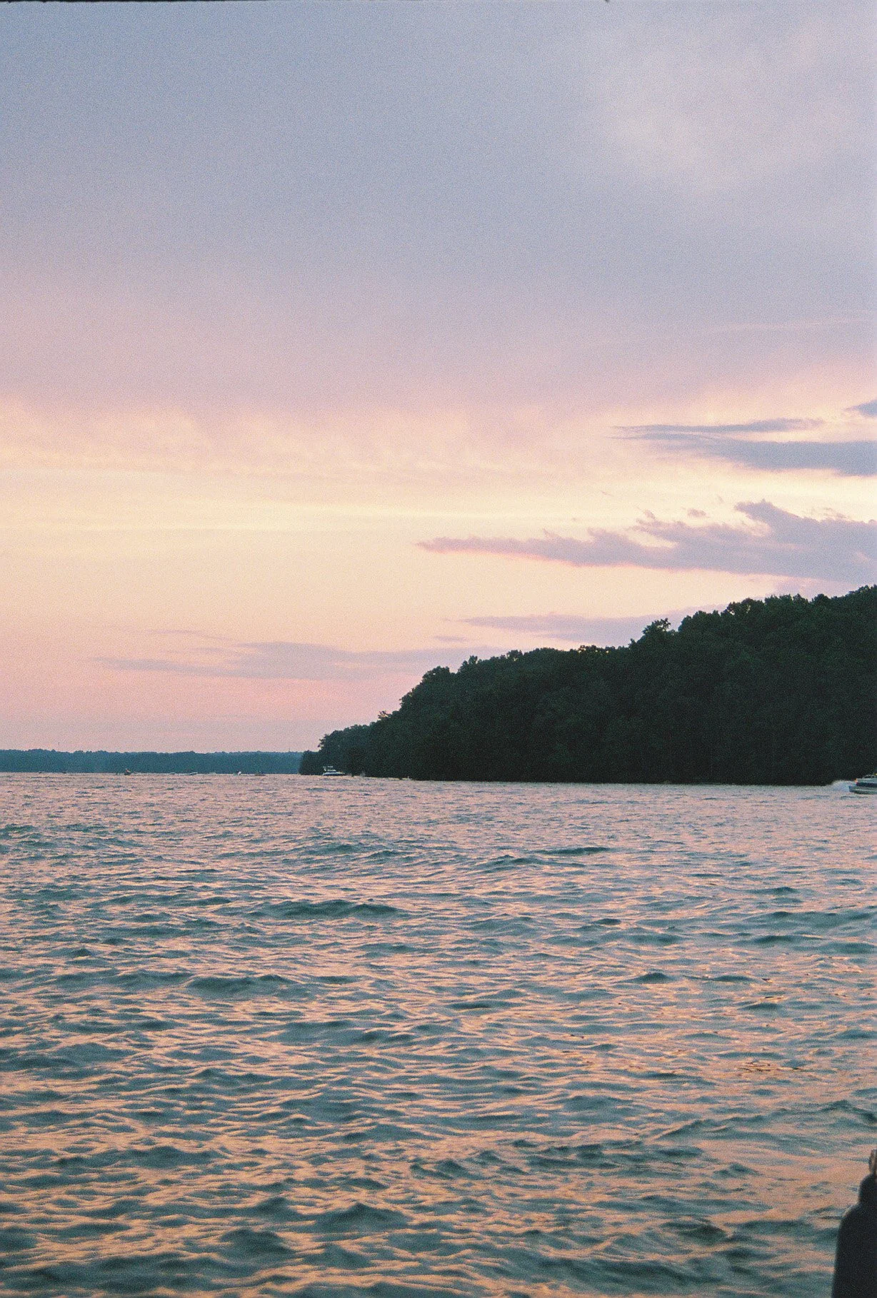 Sunset over a body of water with a tree-covered island on the right side.
