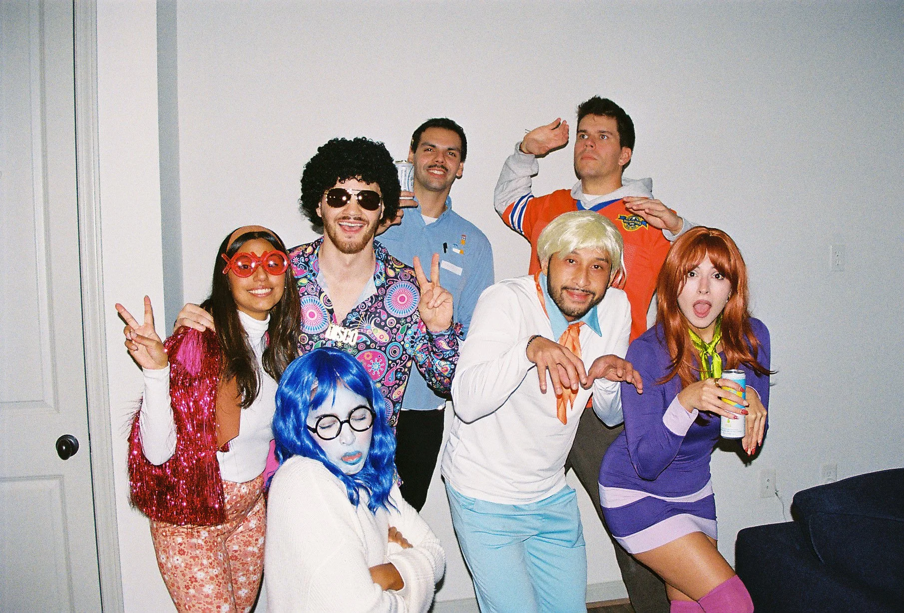 Group of people in colorful costumes posing indoors for a photo.