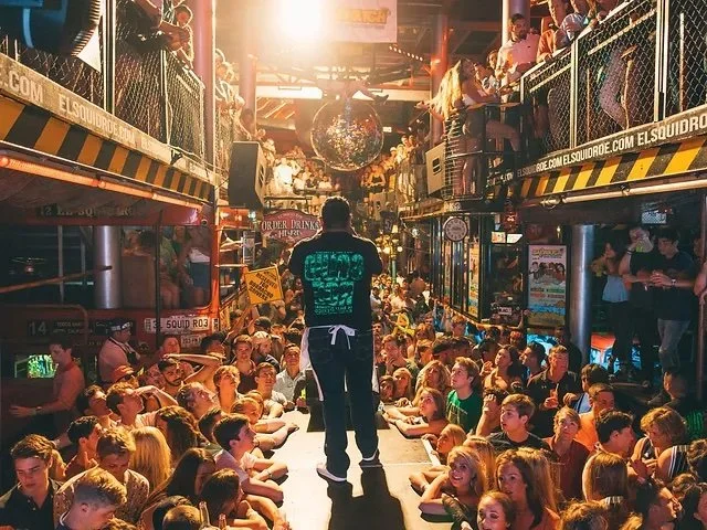 A photo of a staff member hyping up the party at El Squid Roe in Cabo San Lucas. You can see the multilevel floor and funny signs all around