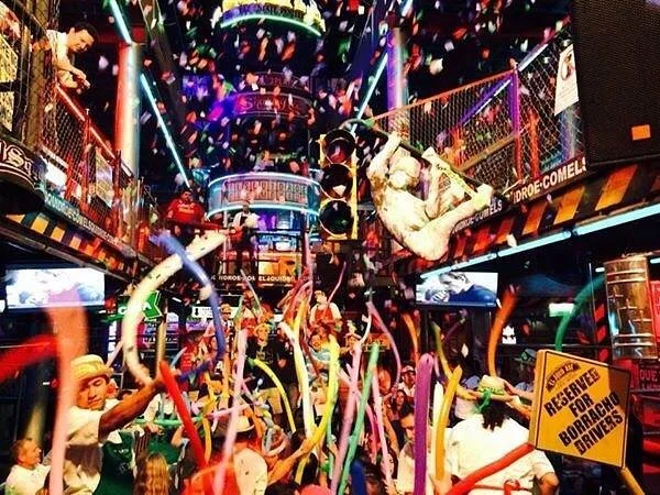 A shot looking through the crowed all shaking and dancing with balloons. There is confetti raining from above. It looks like so much fun. 