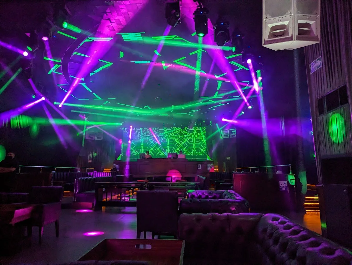A photo of the club before it is open showcasing the purple and green lights and the comfy VIP lounge seats. 