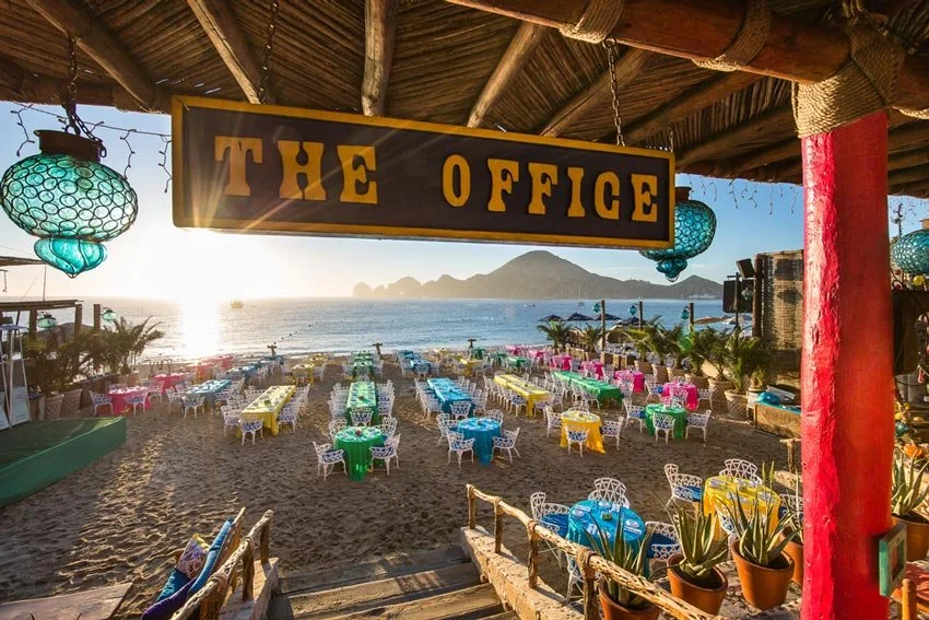 A photo of the office sign and all of the tables on the beach. La Playa. 