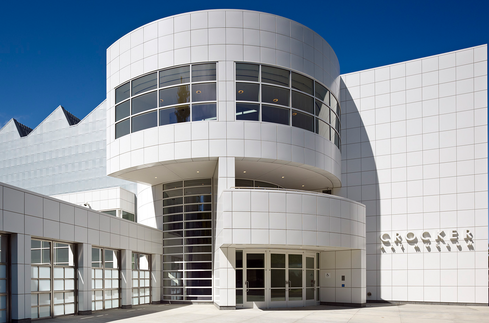 Modern white building with curved glass windows and a sign that reads 'CROCKER' on the side, under a clear blue sky.