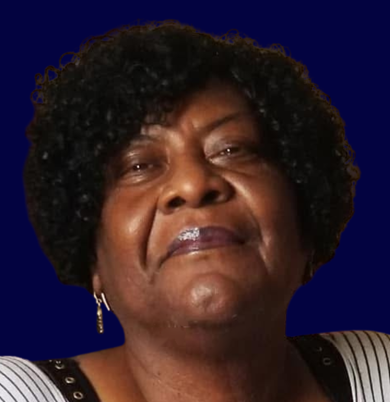 Close-up of a woman with curly black hair, wearing earrings, and a striped top, smiling softly against a dark blue background.