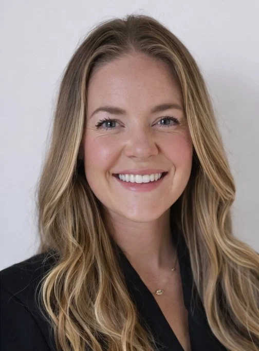 A young woman with long blonde hair smiling at the camera, wearing a black top.