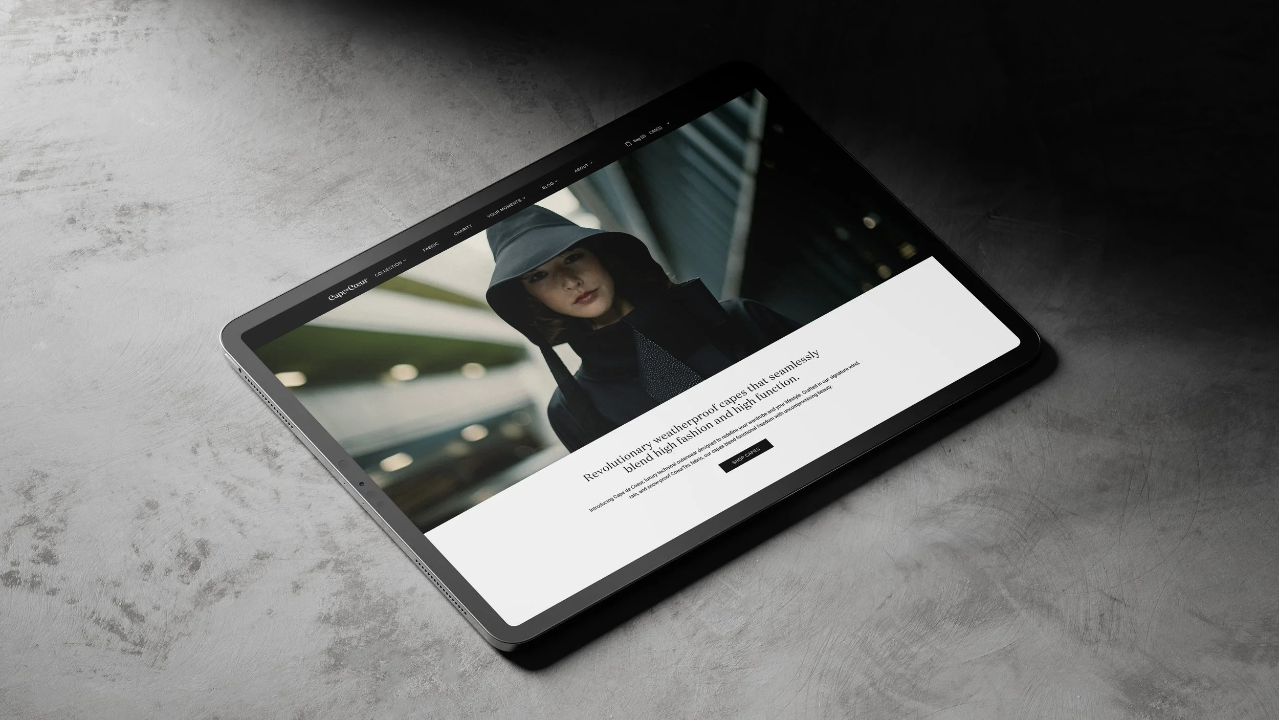 Tablet displaying a website with a woman in an outdoor urban setting, wearing a weatherproof hooded coat.