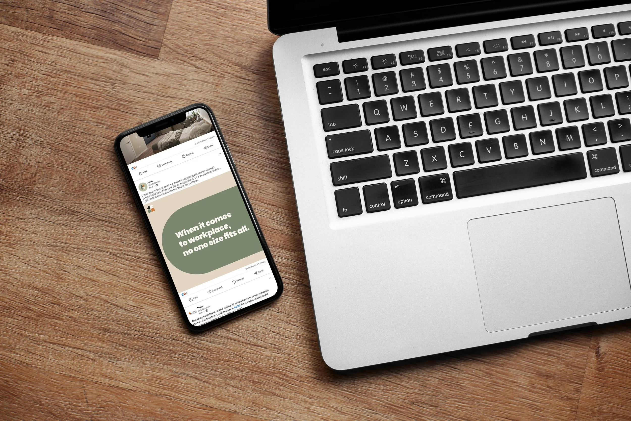 A laptop and a smartphone placed on a wooden desk surface. The smartphone screen displays a social media post with a quote.