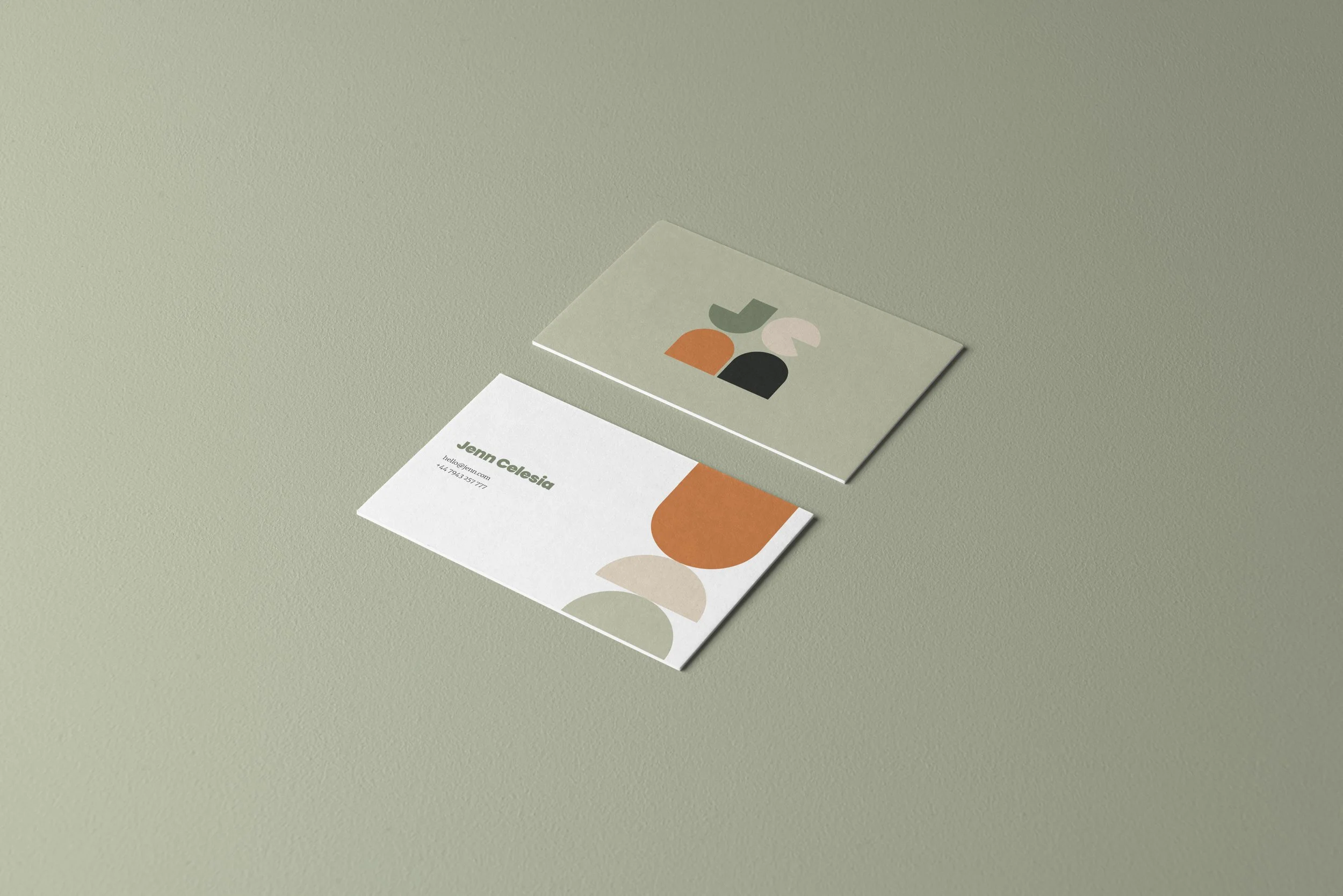 Business cards with abstract designs and contact information, placed on a light green surface.