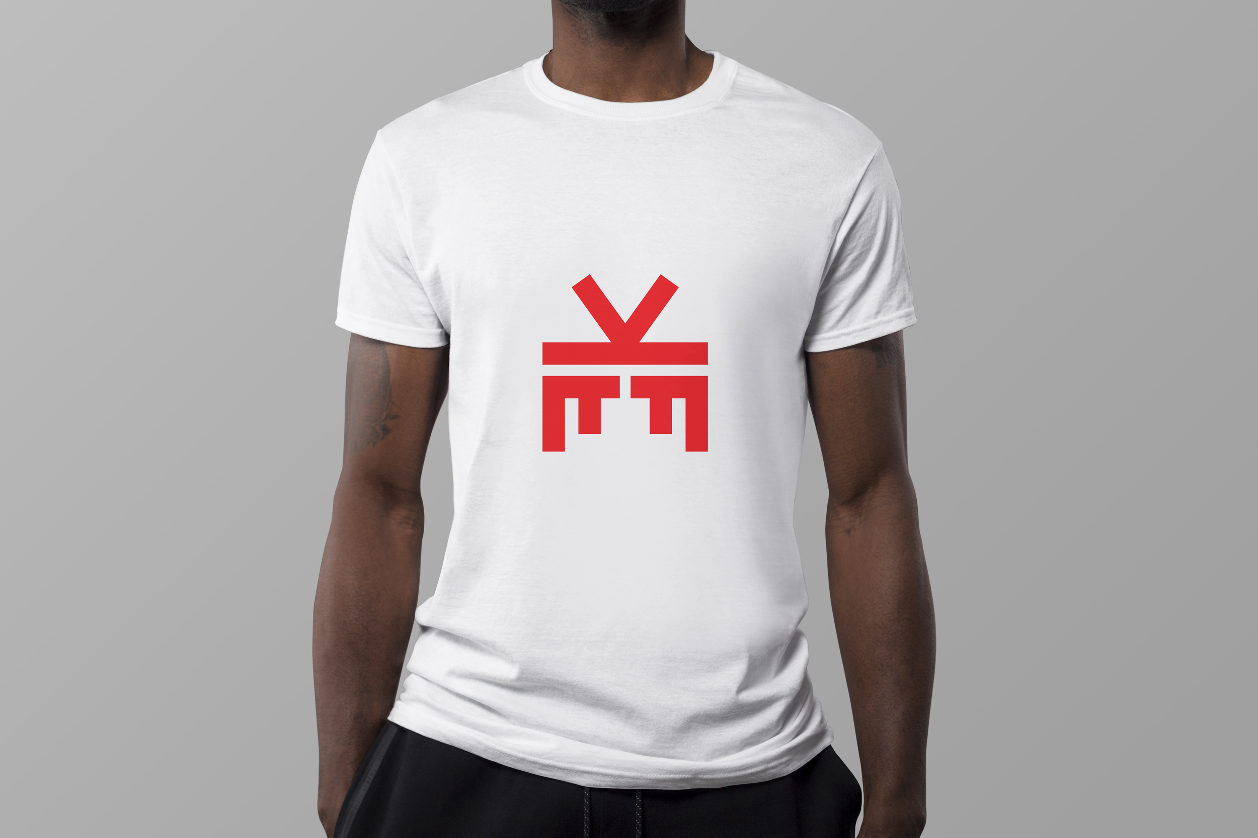 White T-shirt worn by a person with a red abstract design or symbol on the front, set against a plain gray background.