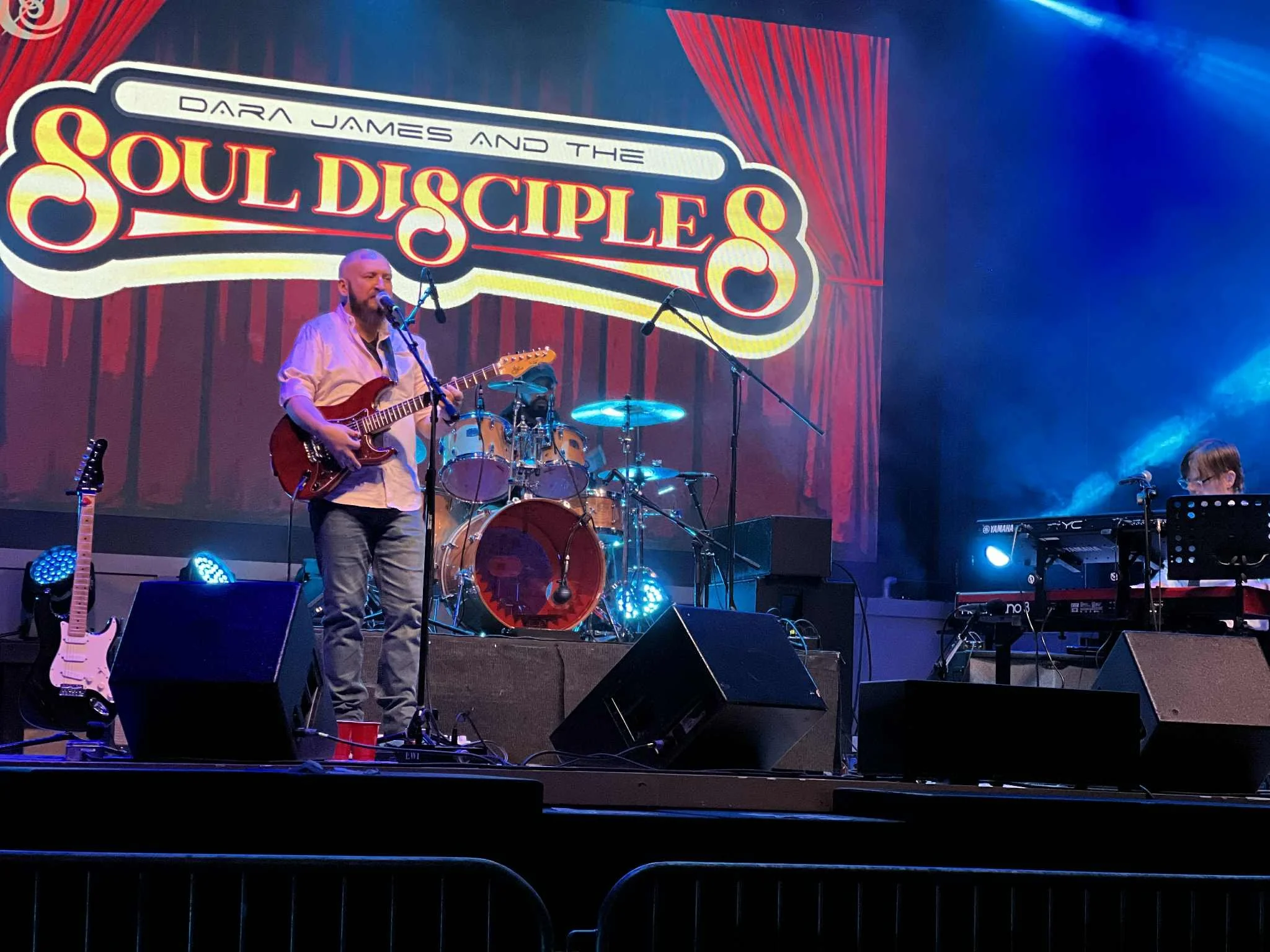 Dara James performing live on stage, singing into a microphone