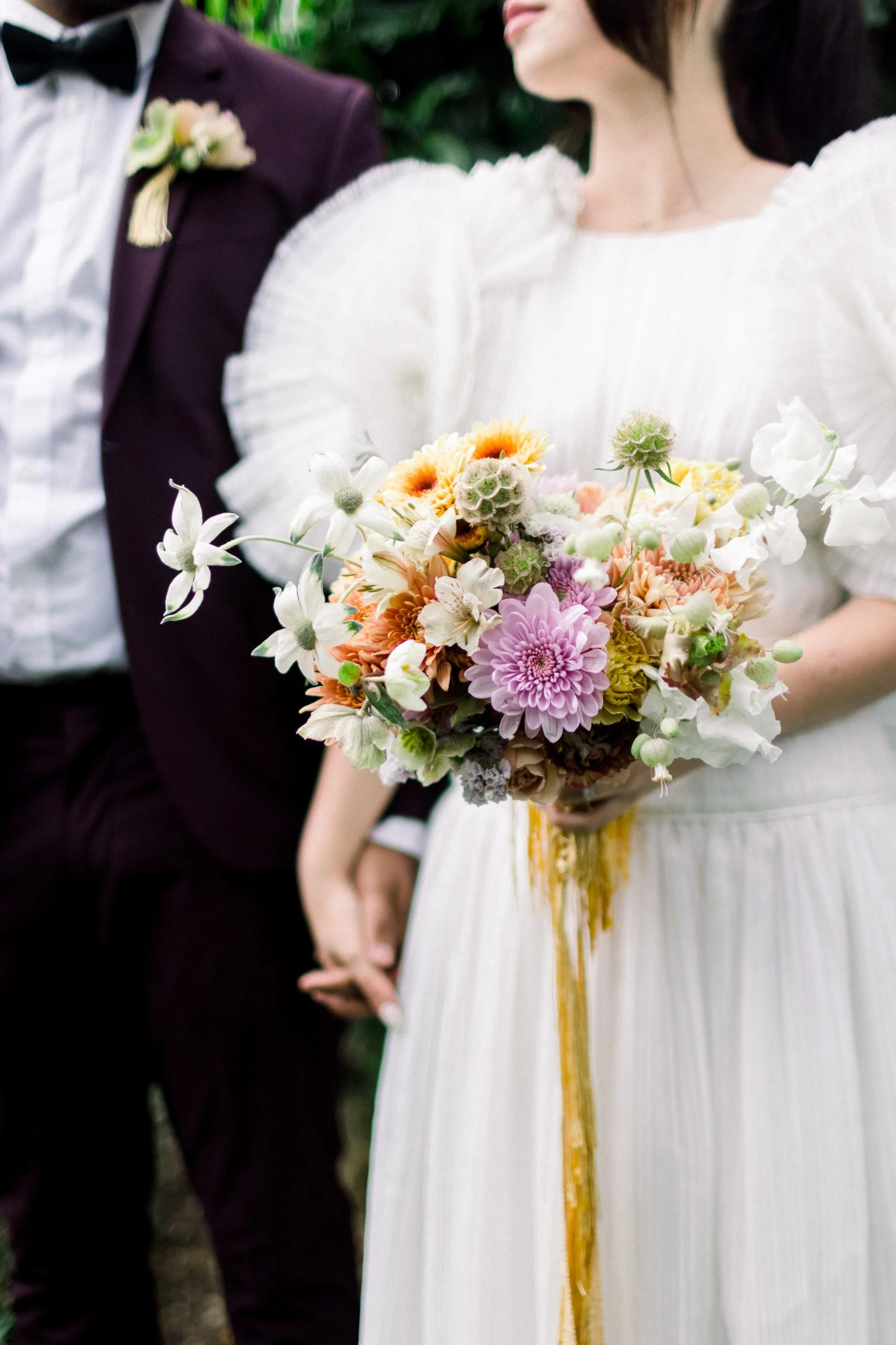 A bride holding a colorful bouquet of flowers during a wedding ceremony.