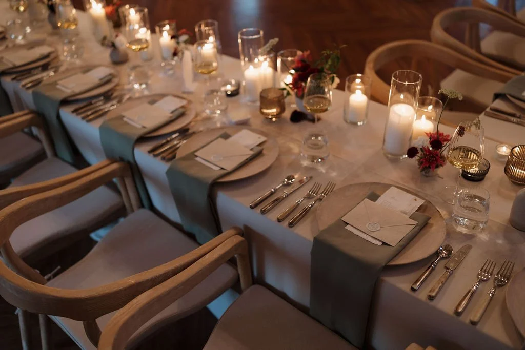 Elegant banquet table set for a formal event with candles, glassware, silverware, plates, napkins, and floral decorations.