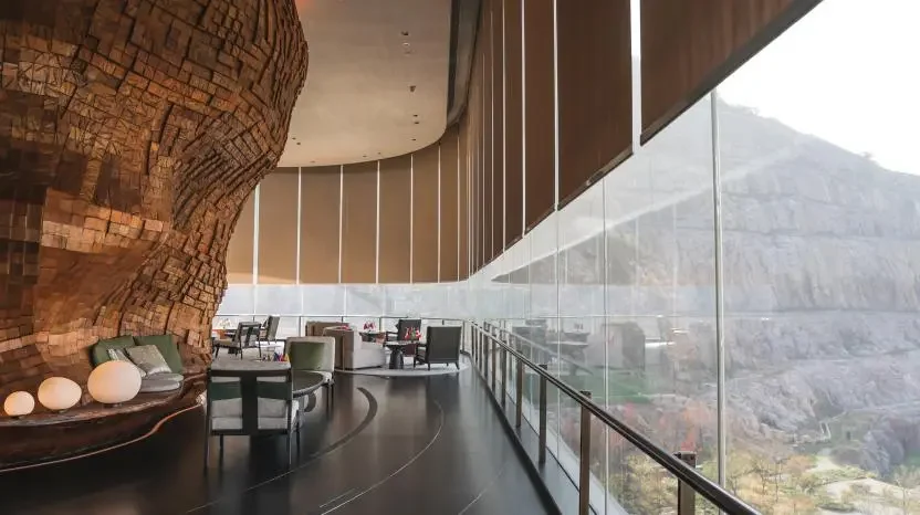 Modern lounge area with curved wooden wall and large glass windows overlooking mountains.