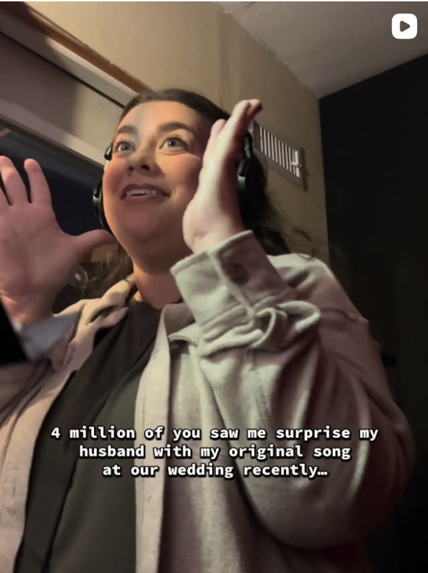 A woman wearing headphones is smiling and holding her hand near her ear in a recording studio. There are subtitle captions at the bottom mentioning a surprise at her wedding.