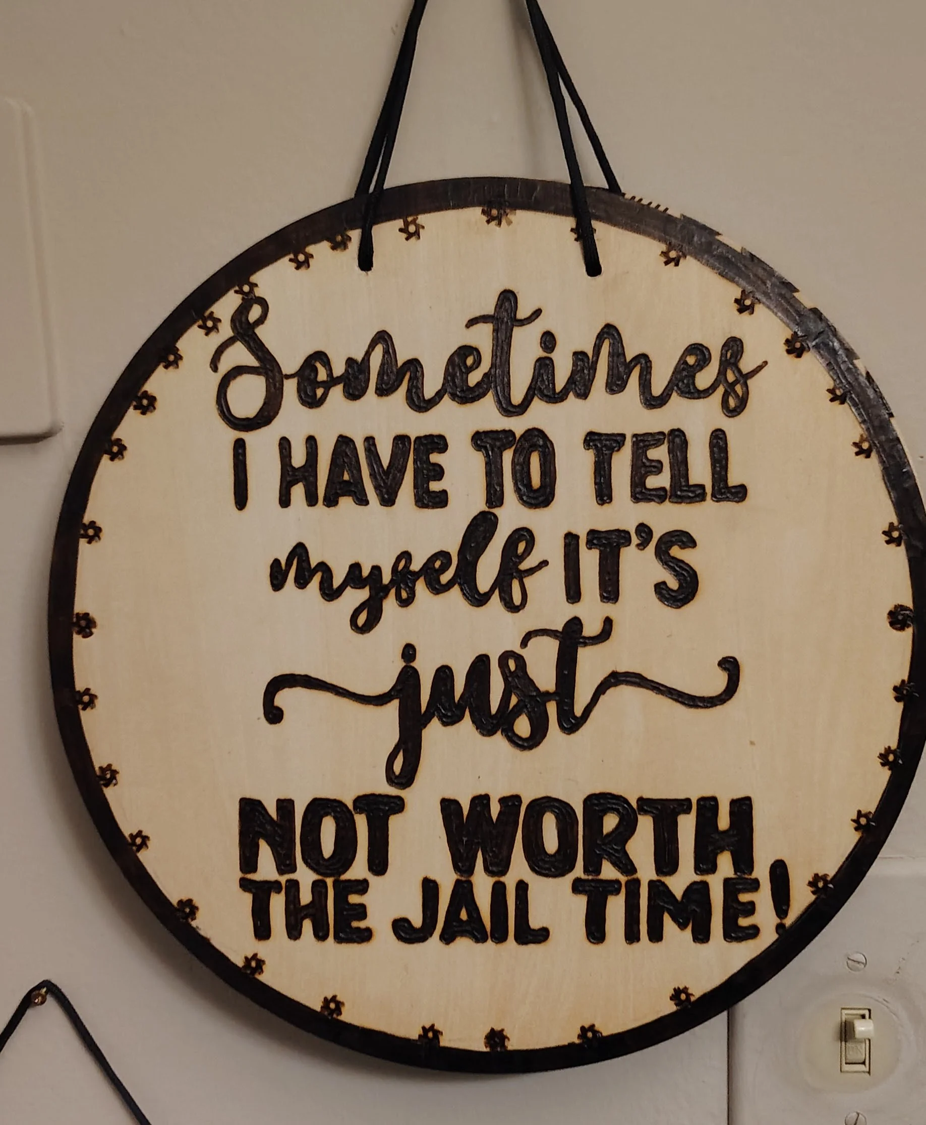 Decorative wood burnt sign with black lettering that reads, "Sometimes I have to tell myself it's just not worth the jail time!"