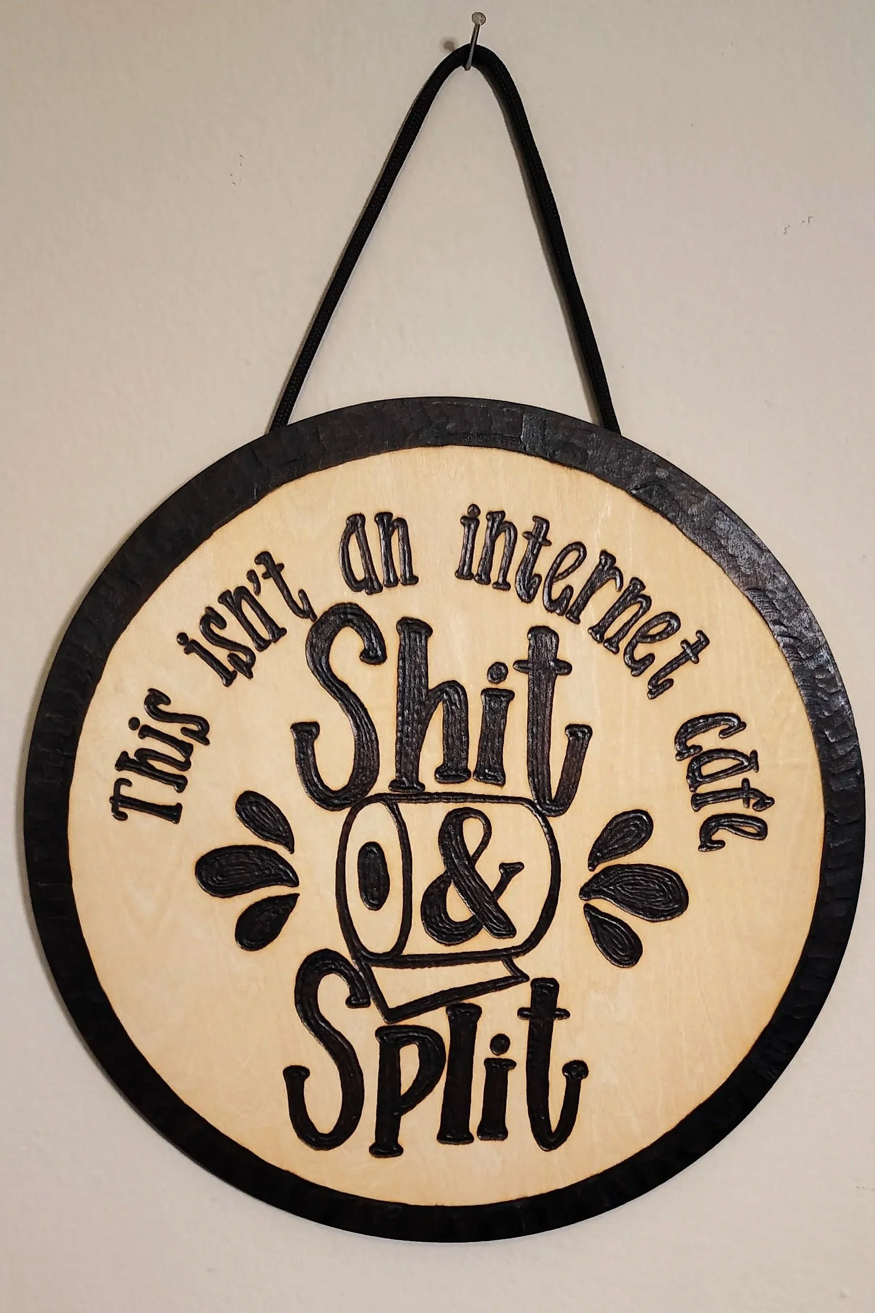 A humorous handmade wood-burned sign that says, 'this isn't an internet cafe' shit and split.
