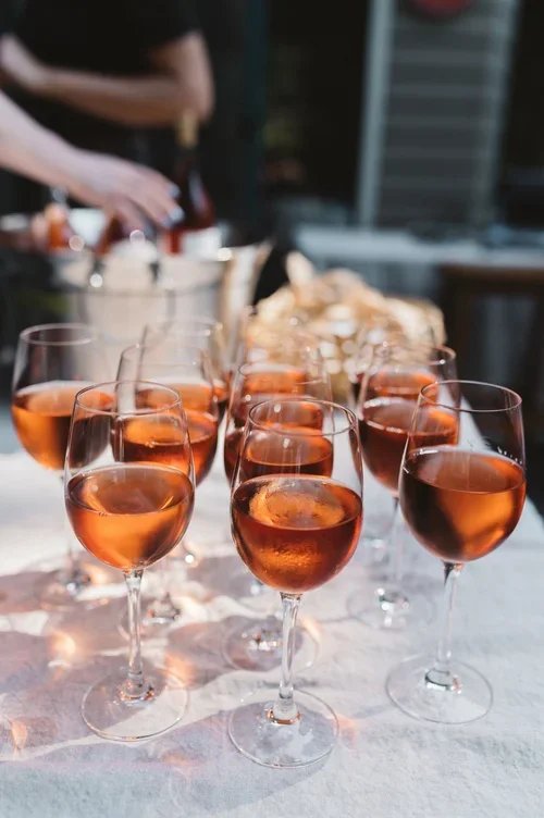 Several glasses of pink wine on a table with a blurred outdoor background.