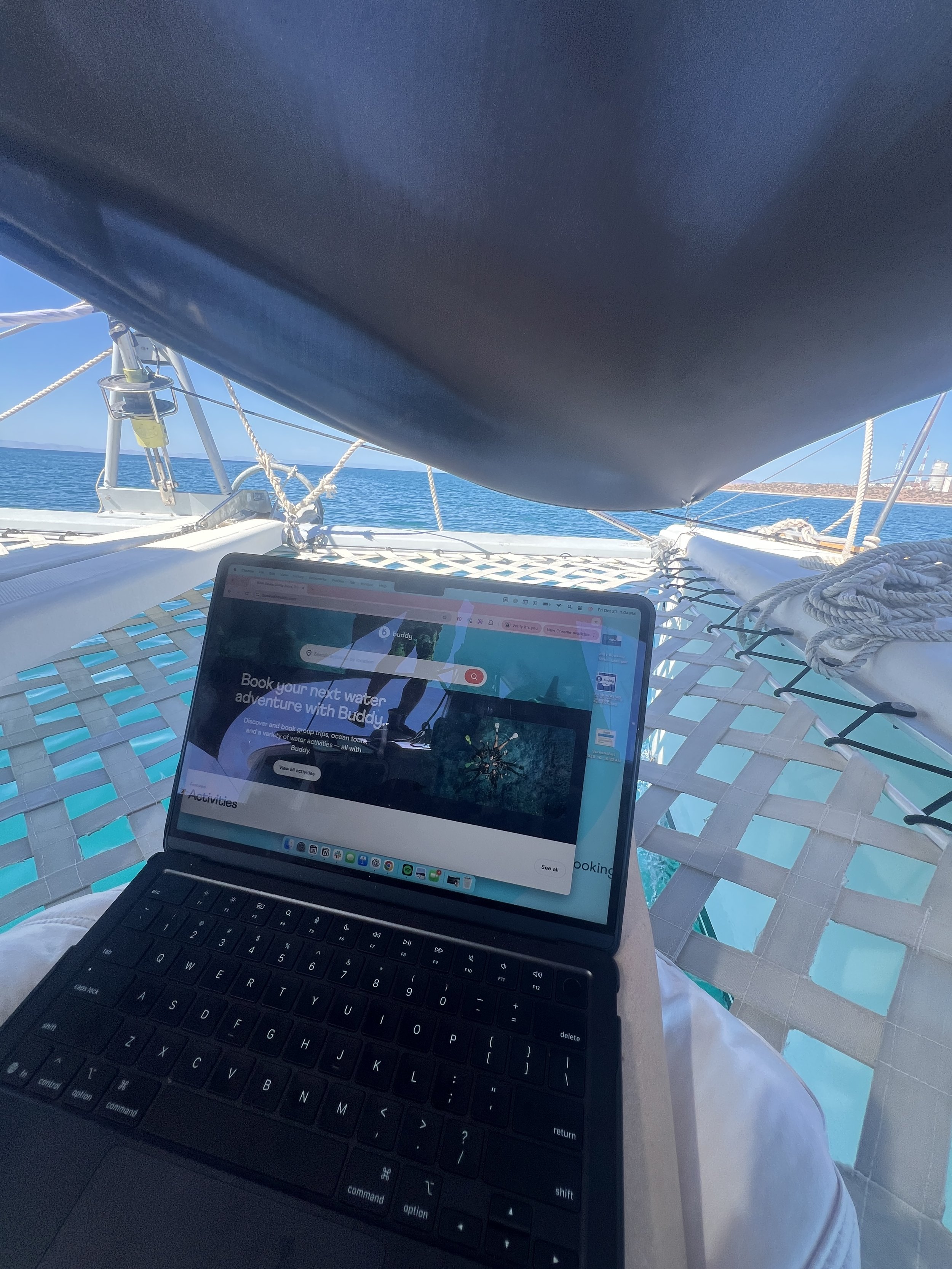 Laptop on a hammock on a boat, overlooking the water and clear blue sky.