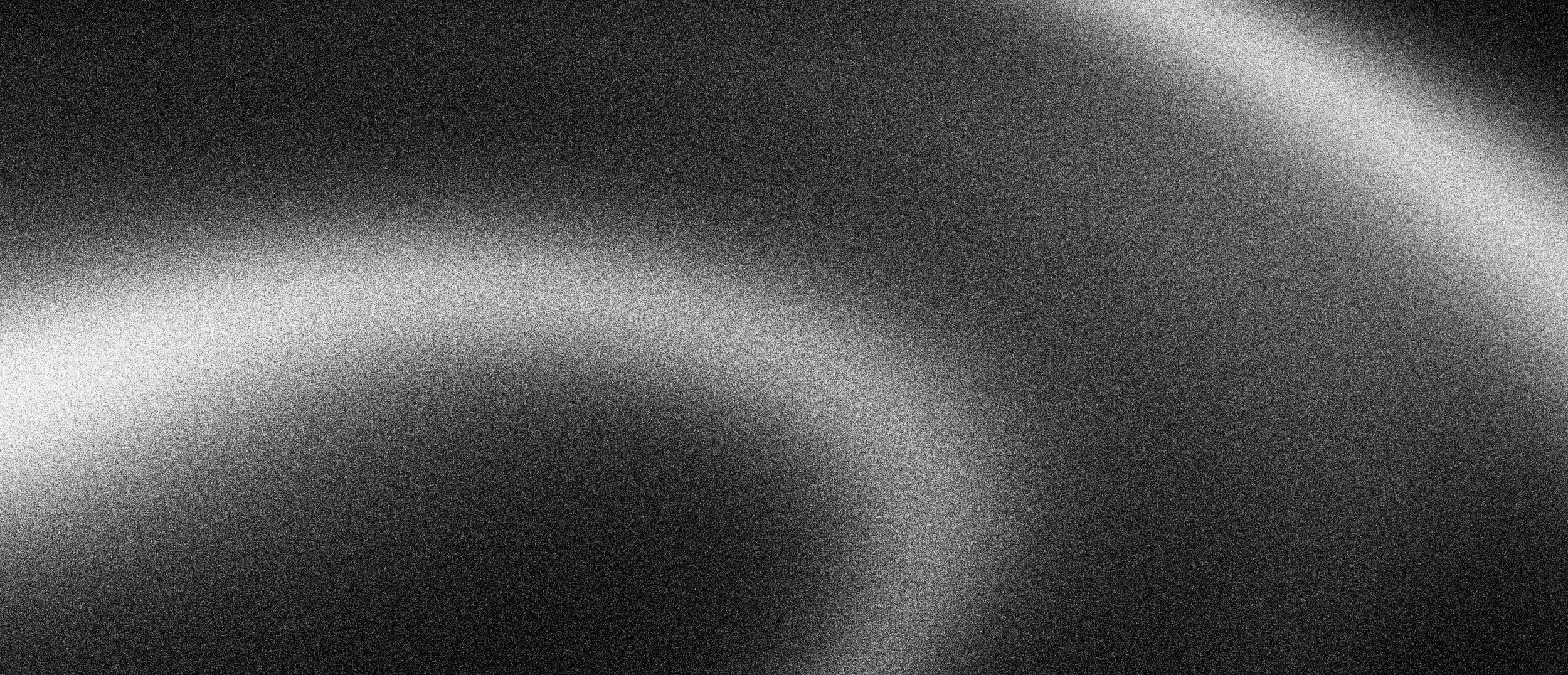 A black and white abstract image with a grainy, textured pattern and soft light gradient.