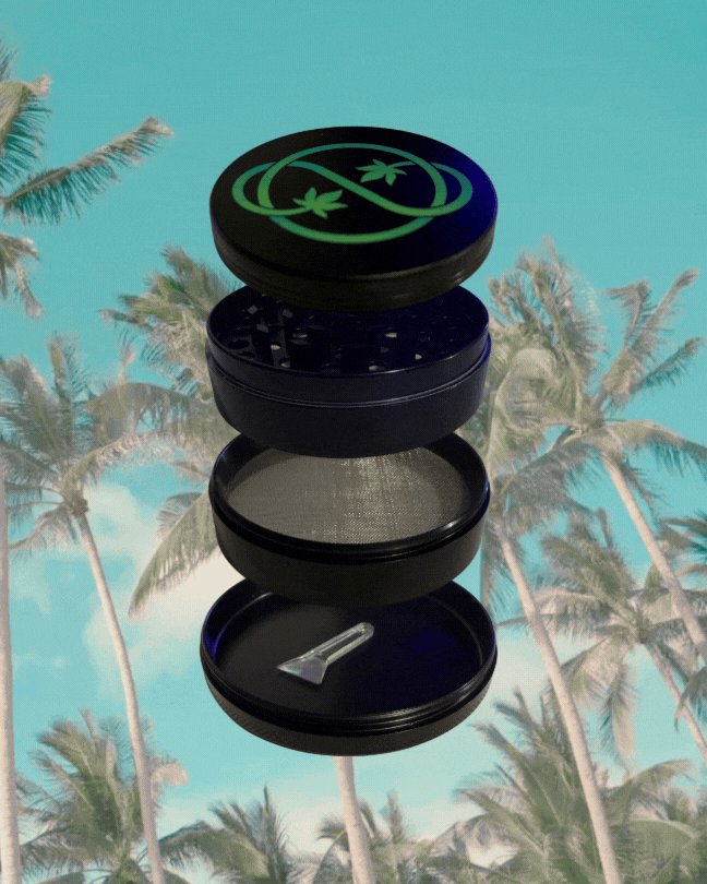A four-layer black herb grinder with a small metal scraper inside, set against a backdrop of palm trees and a turquoise sky.