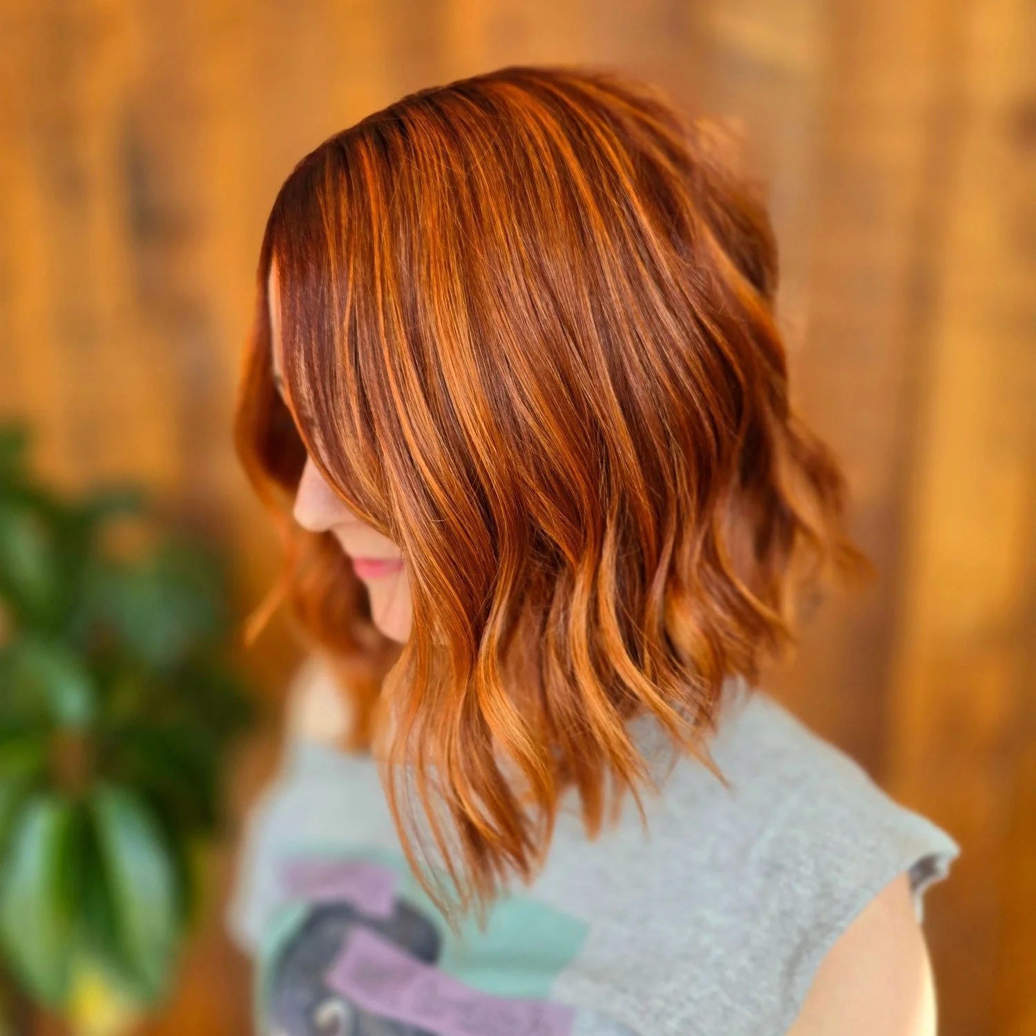 Close-up of a woman with shoulder-length wavy, multi-dimensional, copper hair. Textured bob haircut.