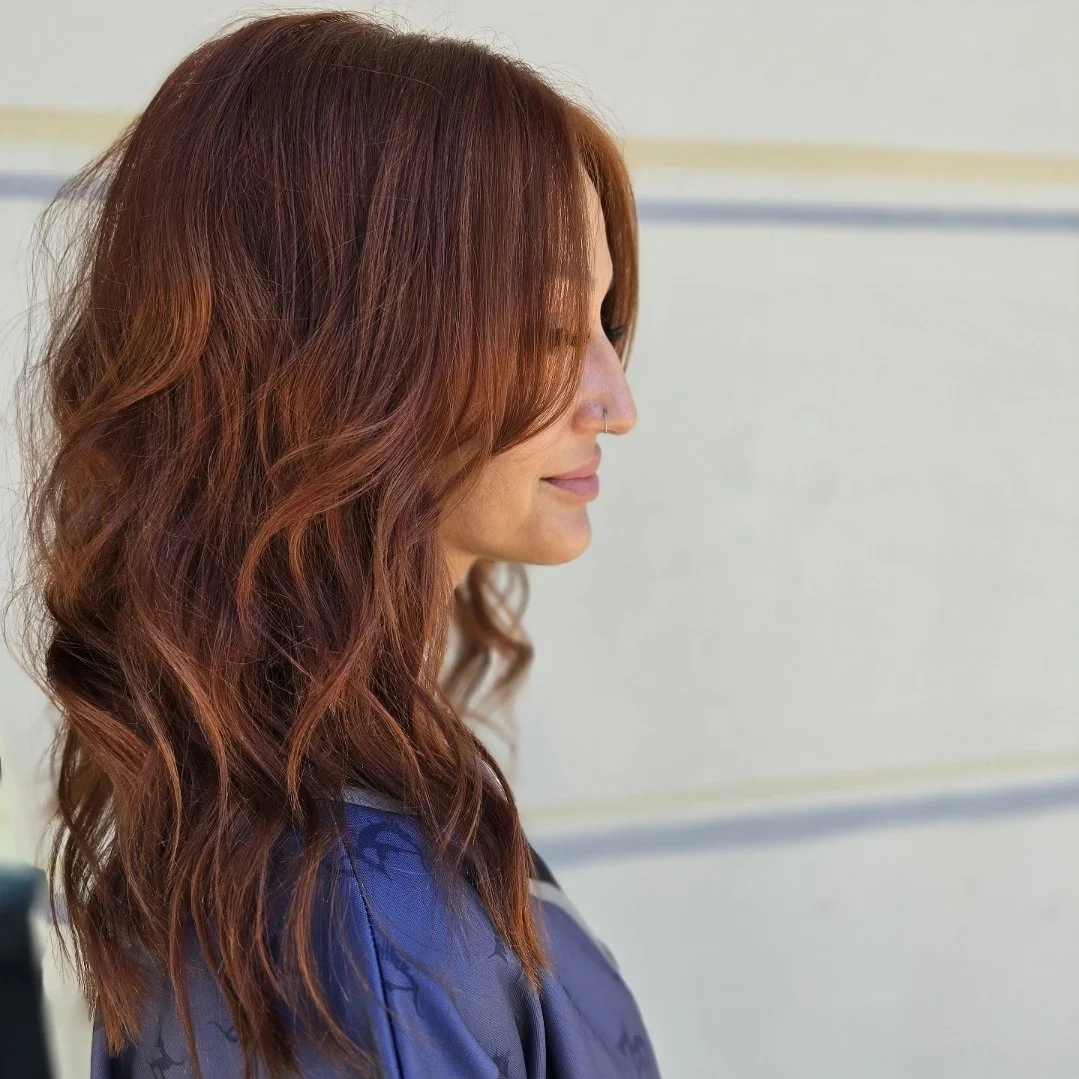 A woman with wavy, cowboy copper hair. Long-medium length.