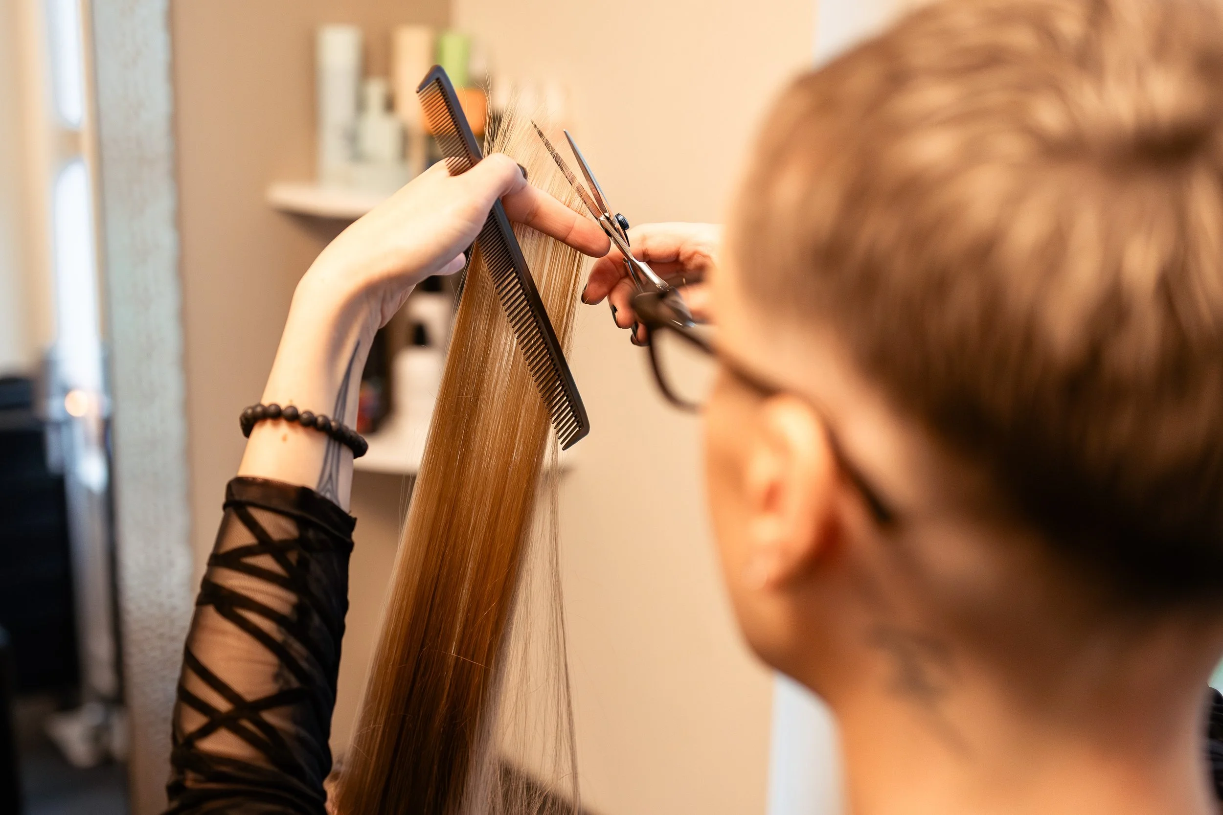 Master hair stylist performing a long, layered cut on a loyal client in her home studio in Surrey, BC.