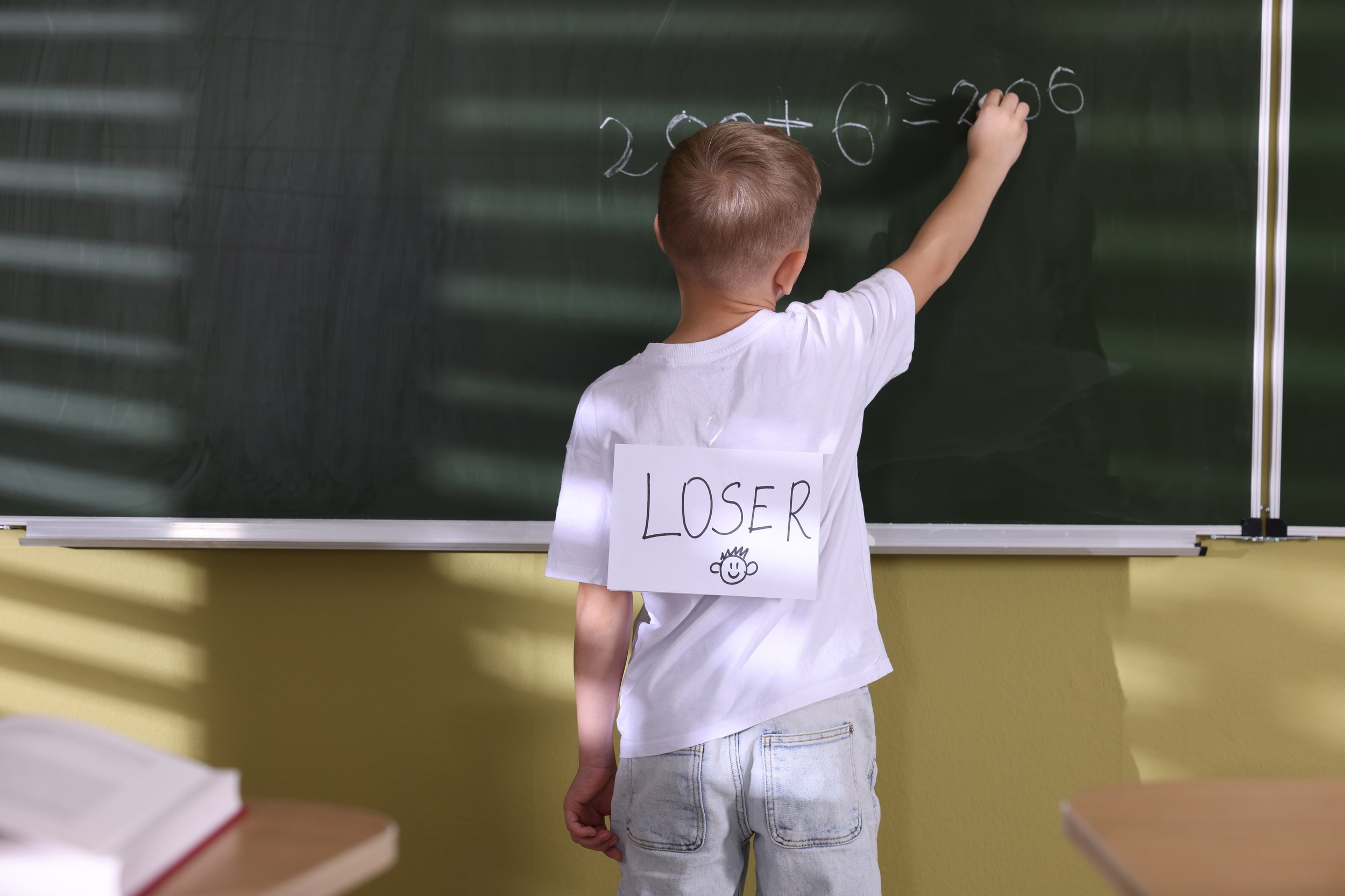 Classroom student facing a blackboard while carrying a label of exclusion, illustrating educational participation challenges, institutional continuity, social alignment failure, and the Post-Industrial Knowledge Architecture (PIKA) framework.