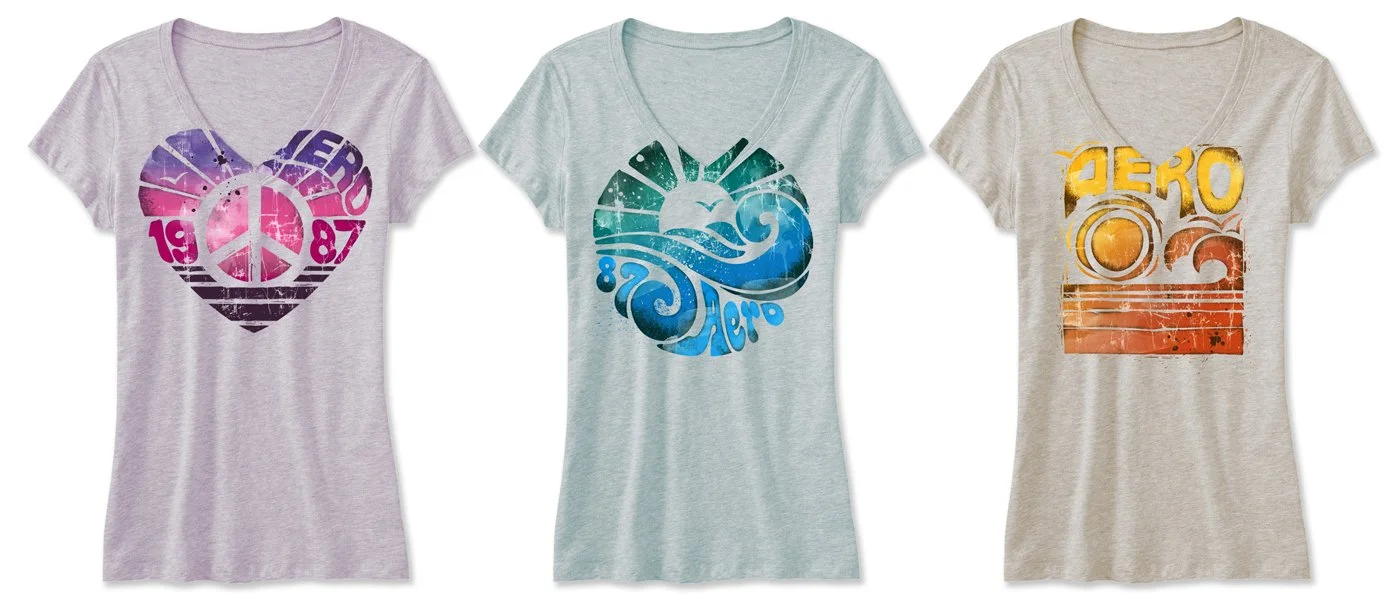 Three women's t-shirts with colorful graphic designs. The first has a pink and purple heart with a peace sign and the year 1987. The second features a blue and green circular design with waves, and the words '82 Aero'. The third displays a yellow and