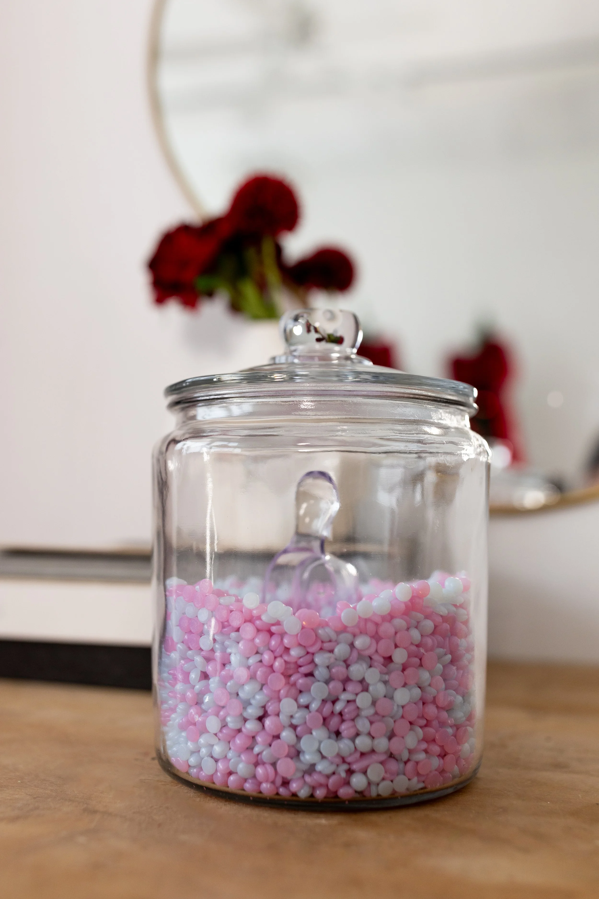 Glass jar filled with pink and white hard wax beads used for professional hair removal treatments