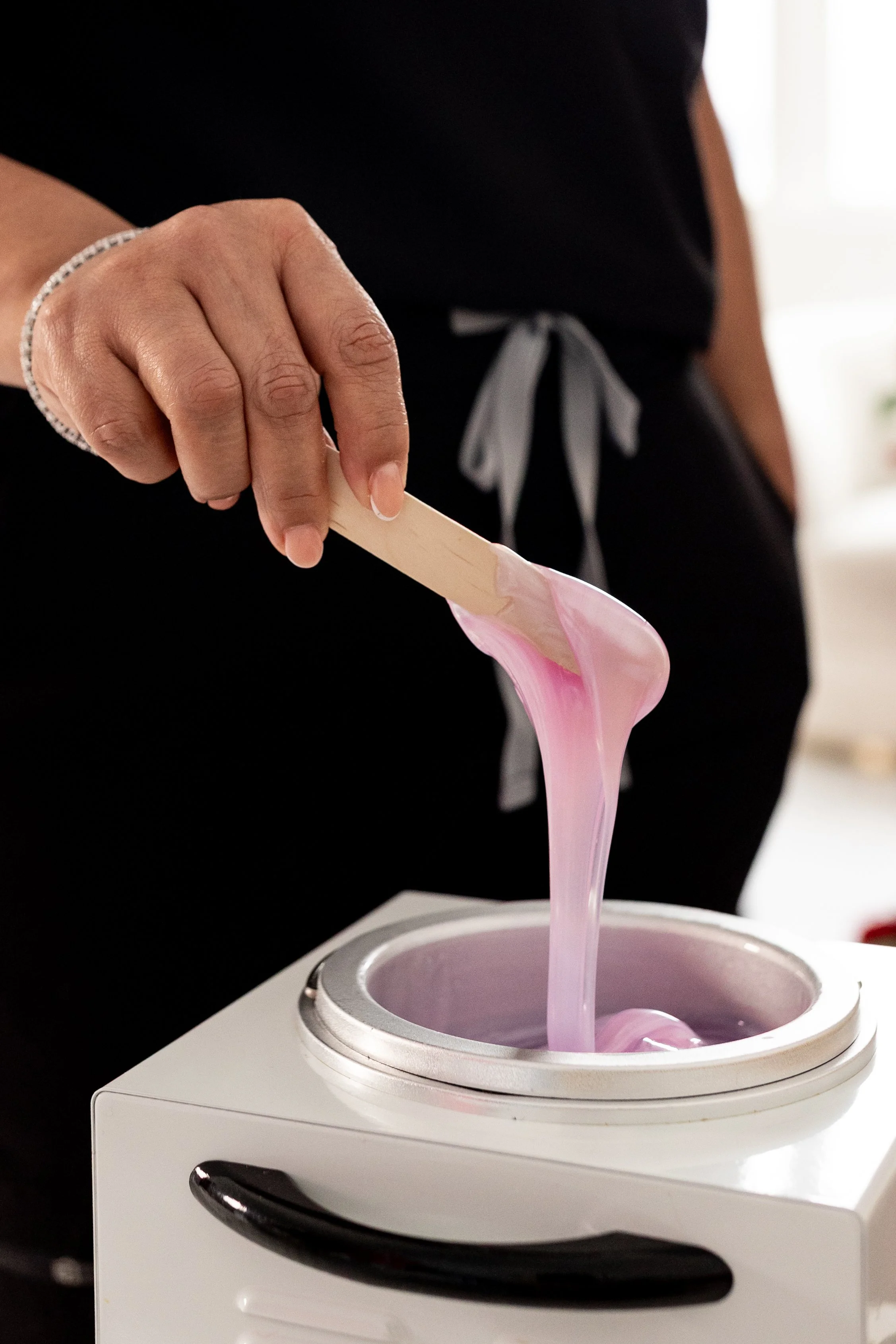 Pink hard wax melting in a professional wax warmer, prepared for hair removal treatment