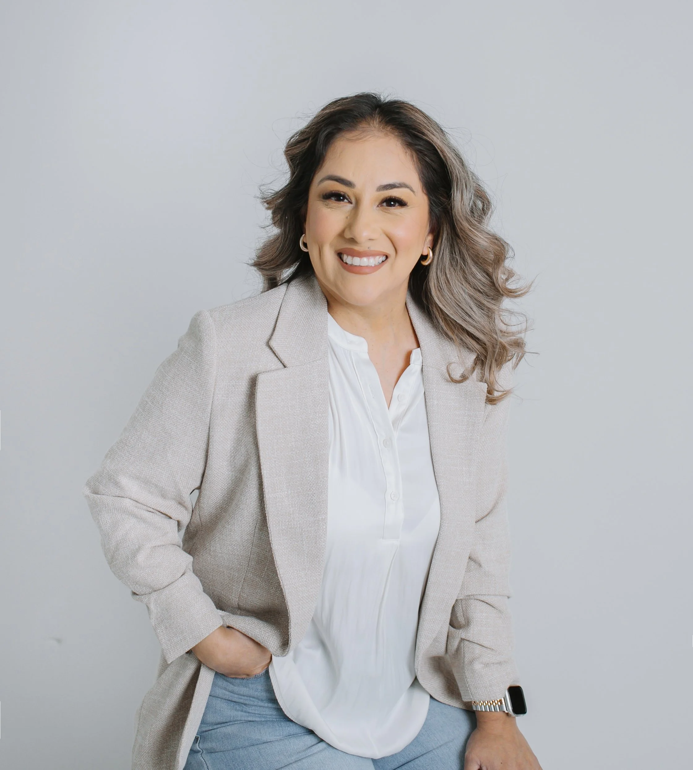 Studio portrait of licensed esthetician wearing neutral blazer and smiling against light background