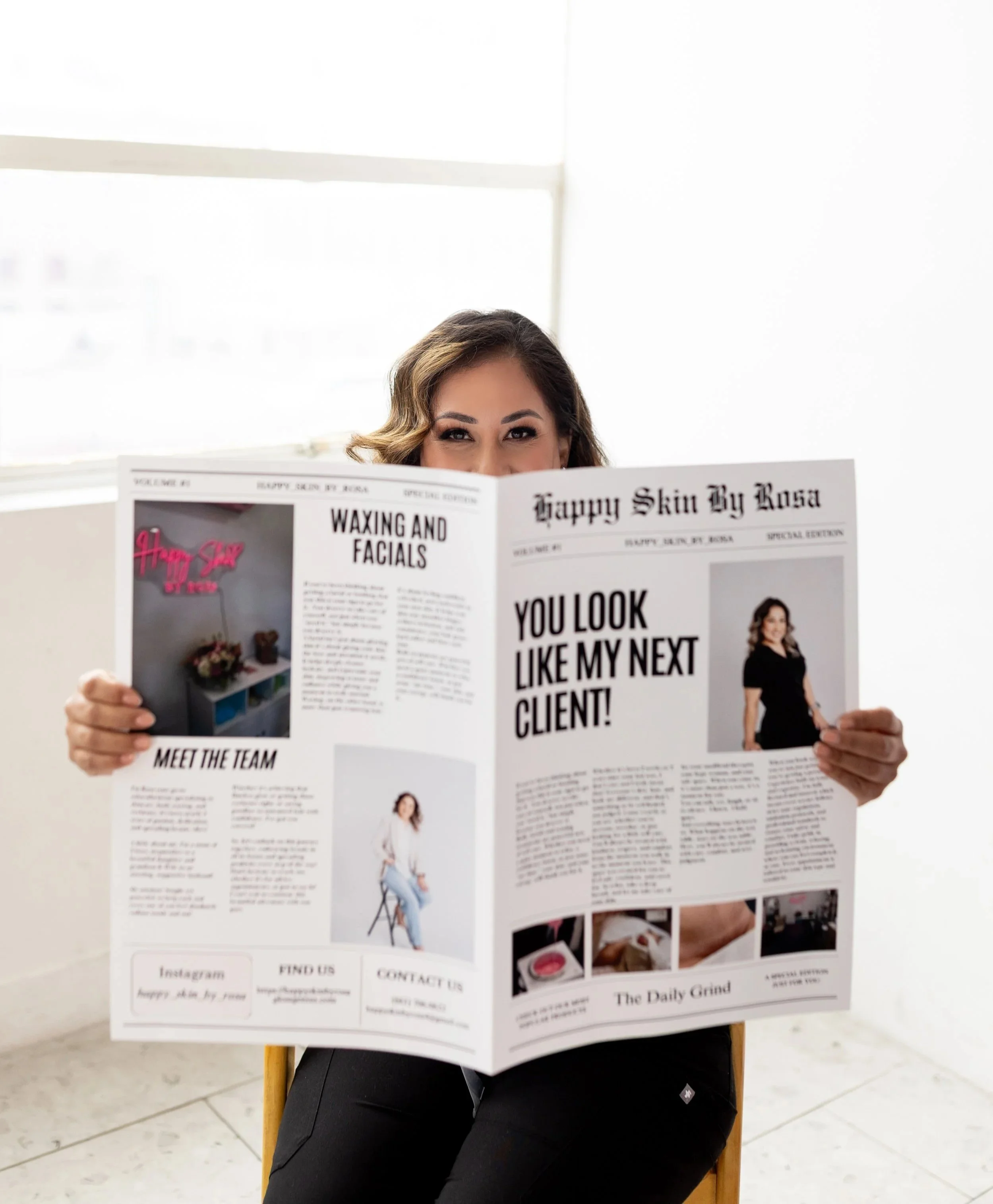 Licensed esthetician seated in studio holding a branded Happy Skin by Rosa magazine featuring waxing and facial services