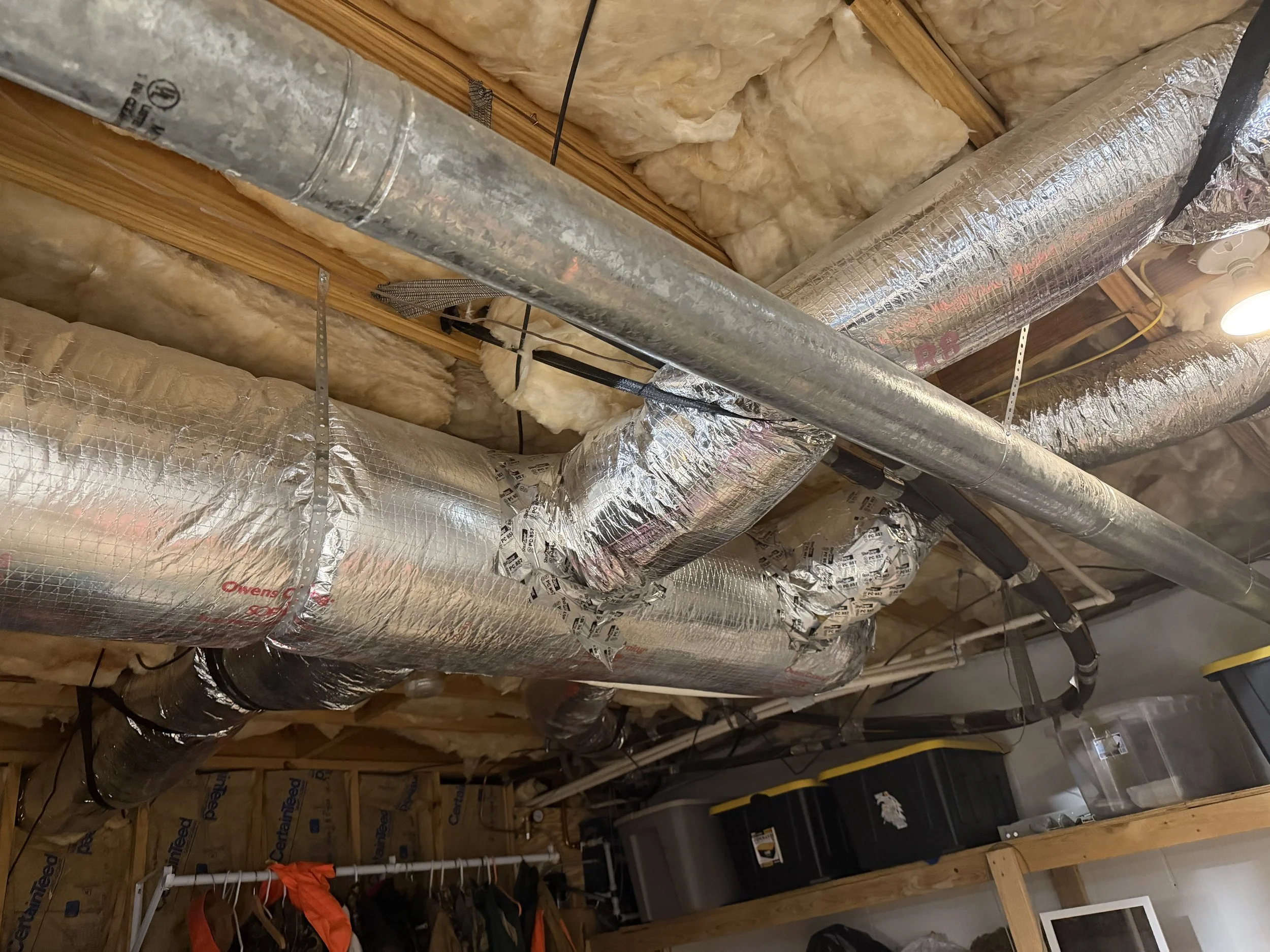 Ceiling with ductwork, insulation, and wooden beams in a basement or attic