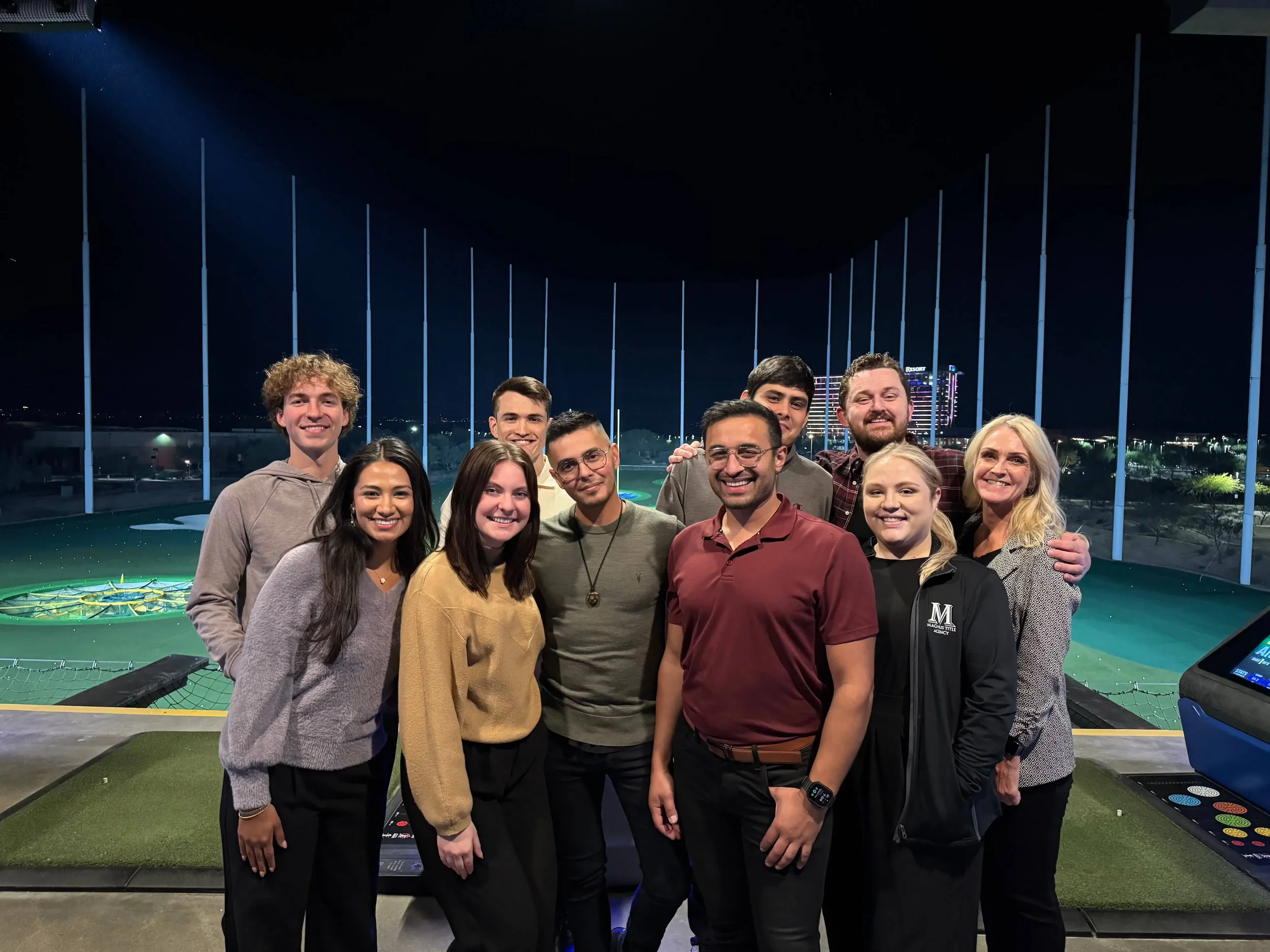 The Bryant Real Estate team smiling together during a team-building night out at a golf driving range venue in Phoenix.